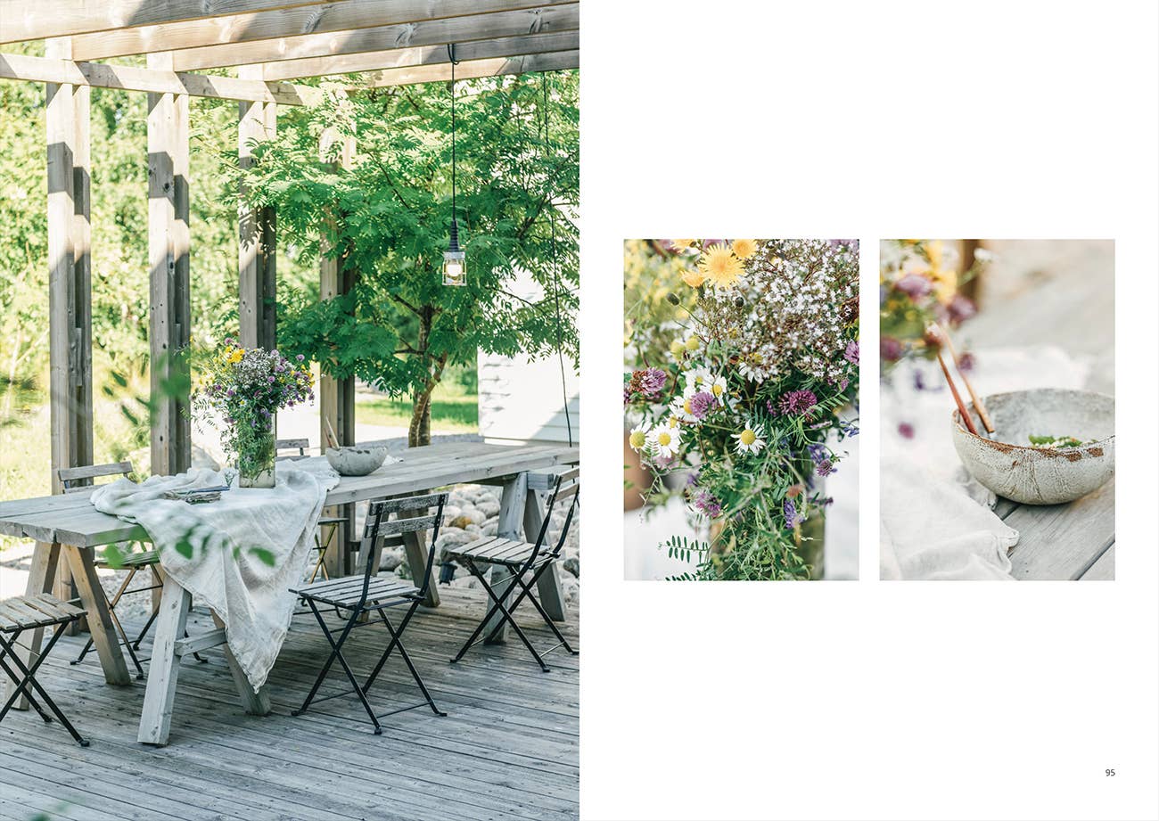 Outdoor setting with a wooden table and chairs on a deck, surrounded by greenery.