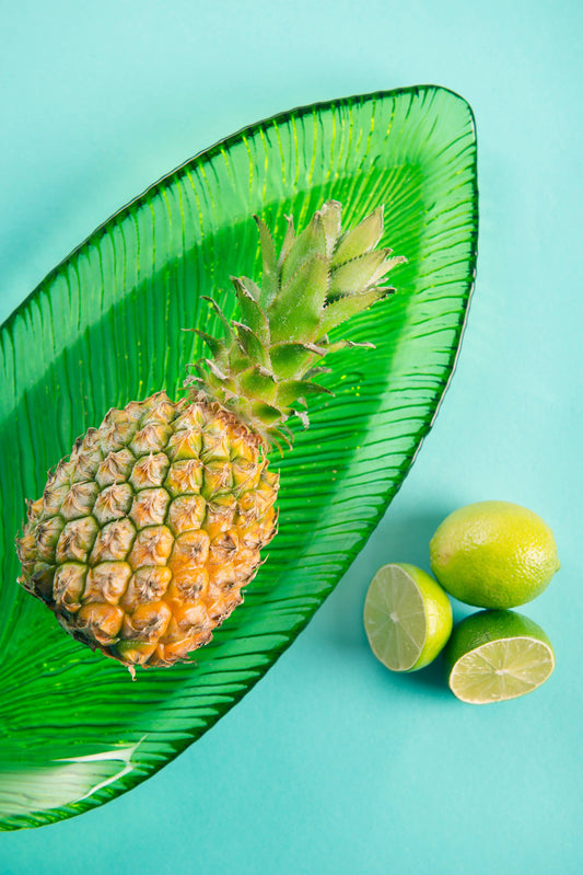Pineapple on a green leaf with limes on a turquoise background