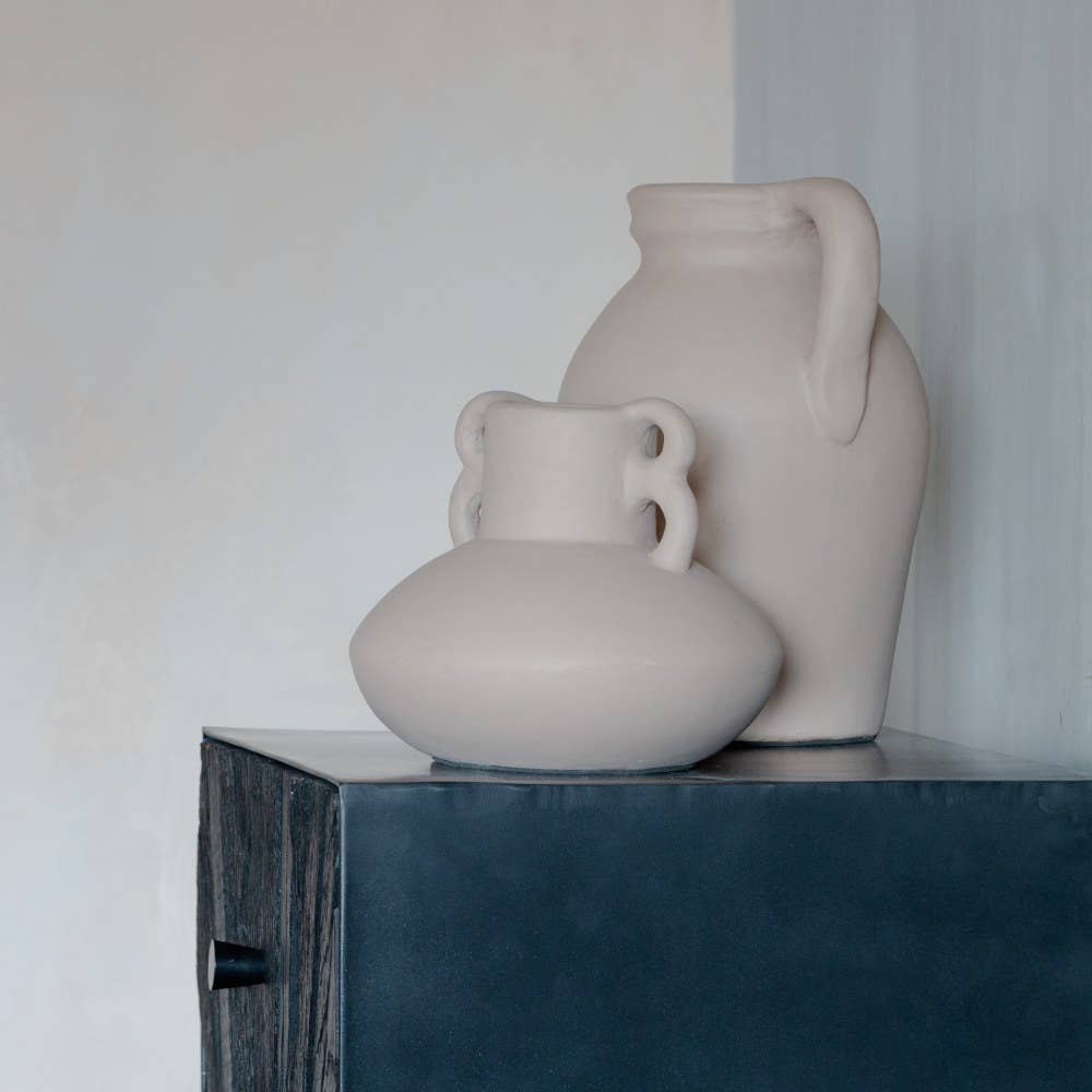 Handcrafted Two terracota beige vases on a dark surface with a light background.