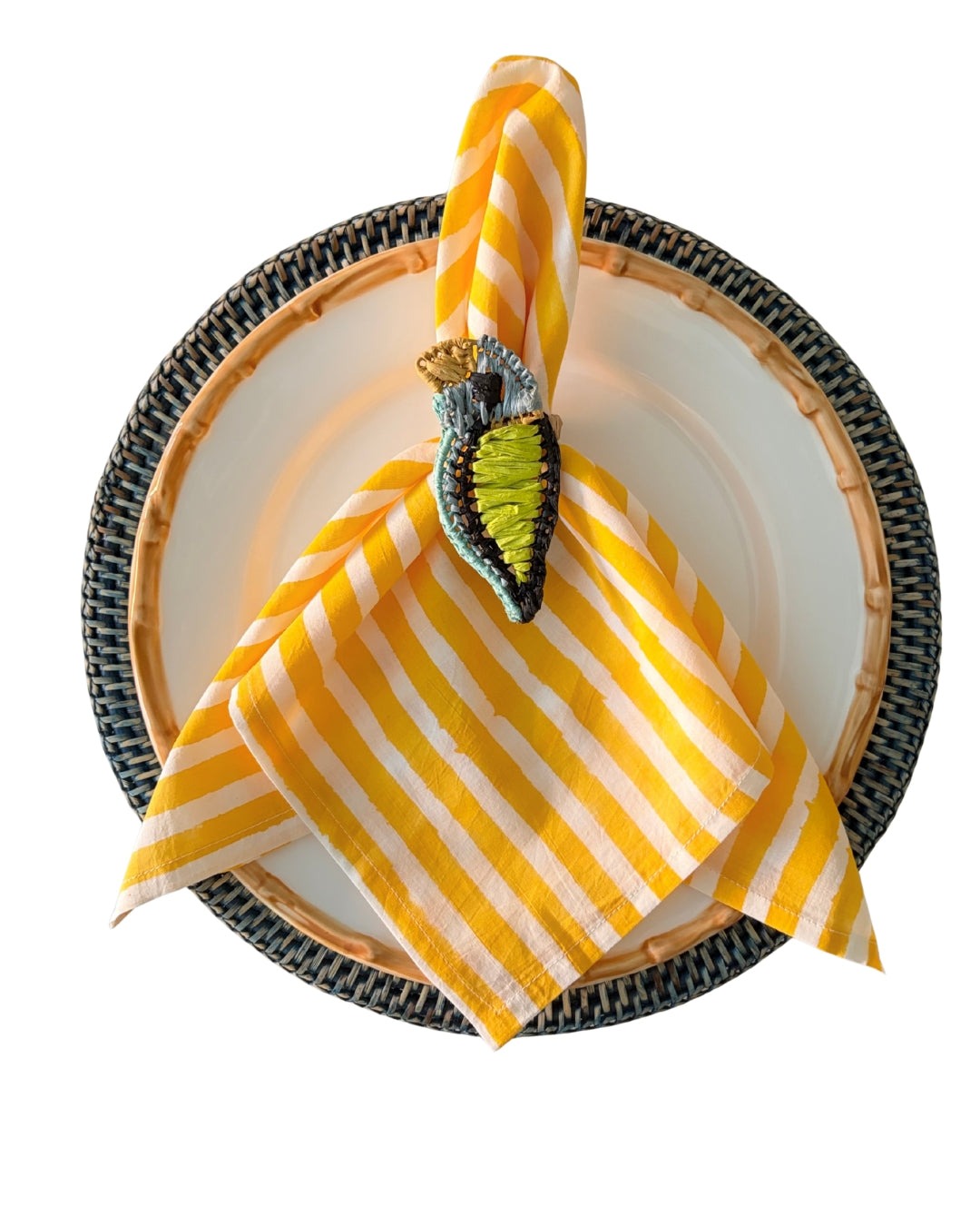 Yellow and white striped napkin on a decorative plate with a decorative napkin ring.