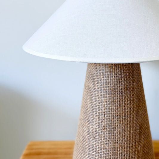 Warm atmospheric glow through the ecru cotton shade of the Sculpt artisan lamp in a dimly lit room.