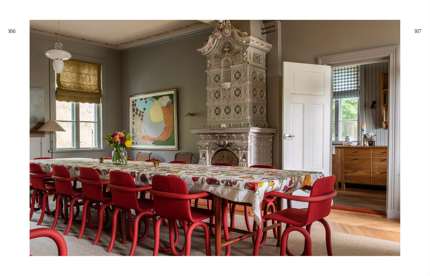 Dining room with red chairs, patterned tablecloth, and decorative fireplace.