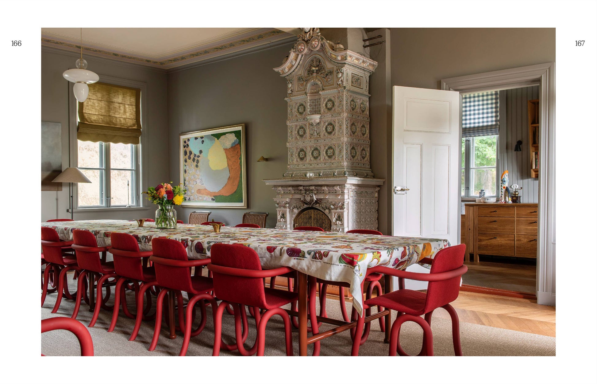Dining room with red chairs, patterned tablecloth, and decorative fireplace.