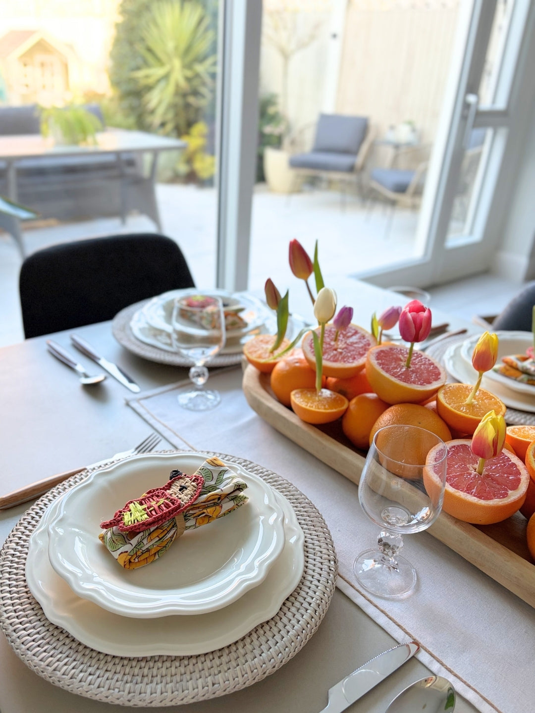 Dining table set with plates, sandwiches, and a fruit platter with garnishes.