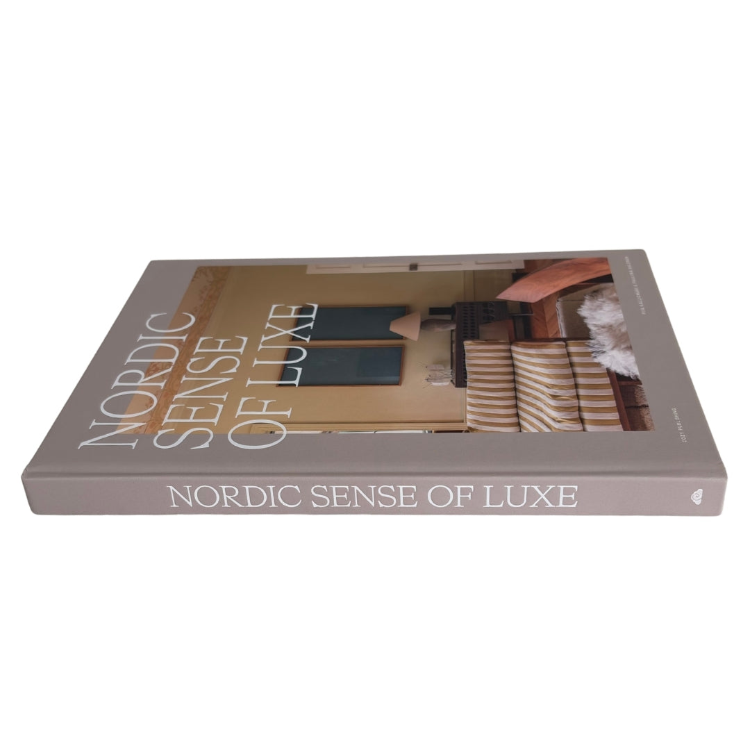 Nordic Sense of Luxe book with a taupe-gray cover featuring a photograph of a cozy interior and large white title text, shown on a plain white background.