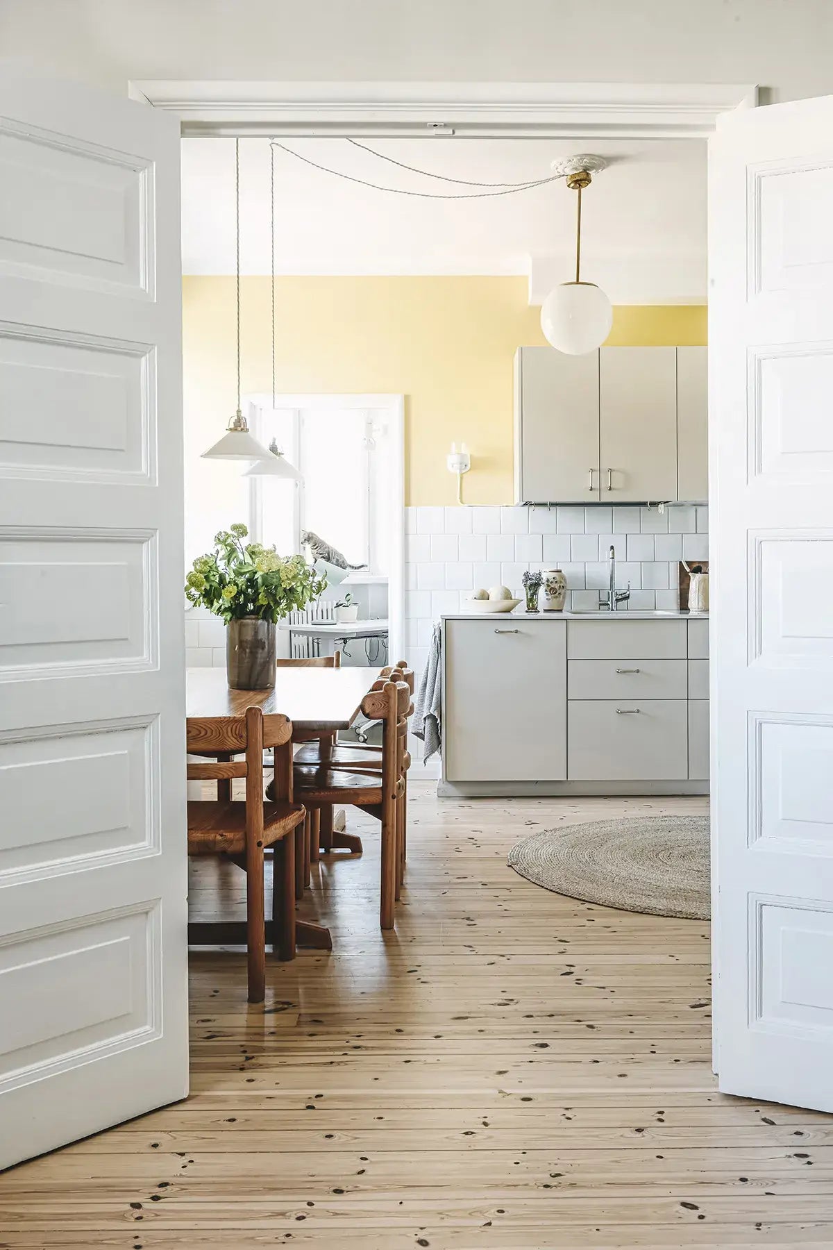 Open door leading to a kitchen with wooden floor and white walls