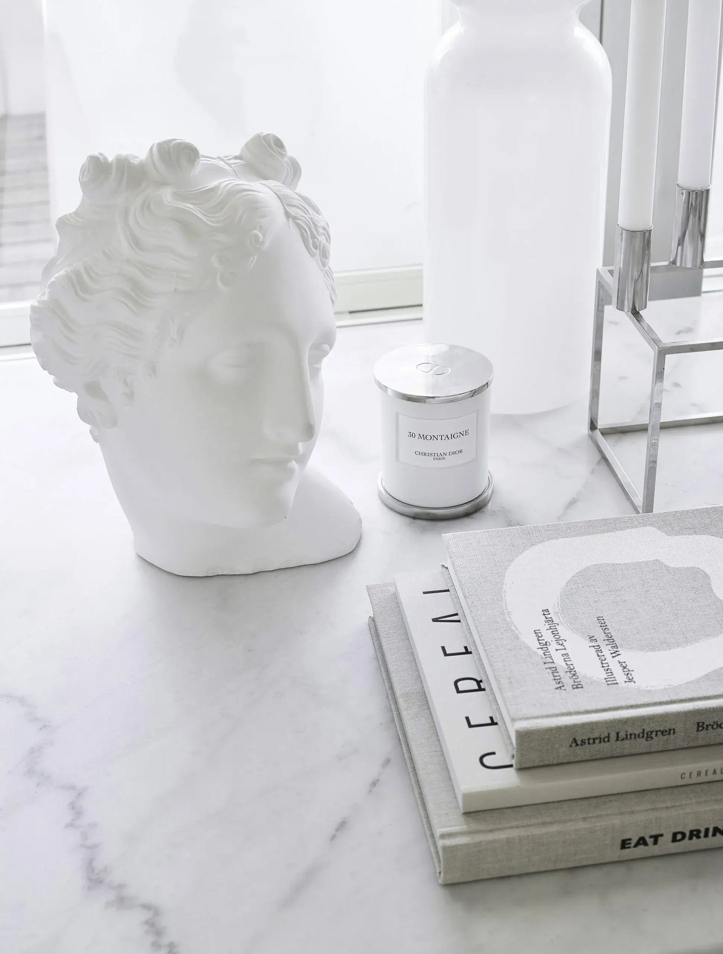 White lion head sculpture on a marble surface with books and a candle