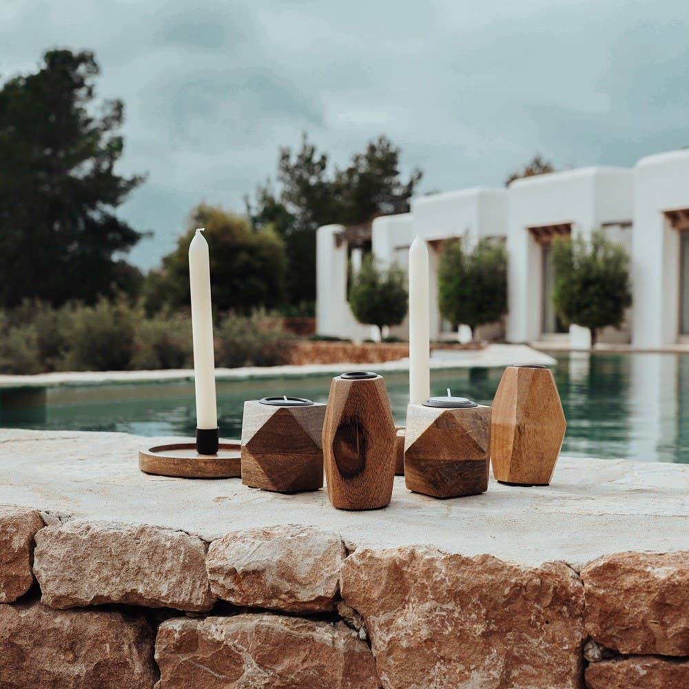 Decorative candles on stone ledge by a poolside with a modern building in the background