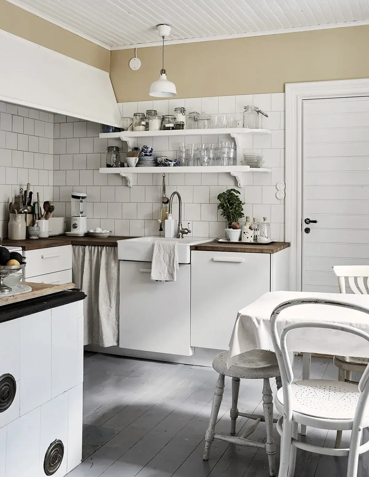 Modern kitchen with white cabinets, wooden countertops, and a dining area.