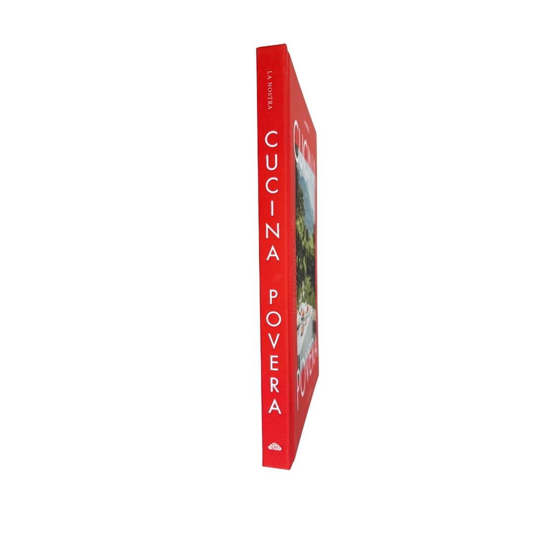 A single hardcover cookbook standing upright on a plain white background. The book is shown in profile, with a bright red spine and cover featuring the title 'CUCINA POVERA' in large white letters and a small food photograph on the front.