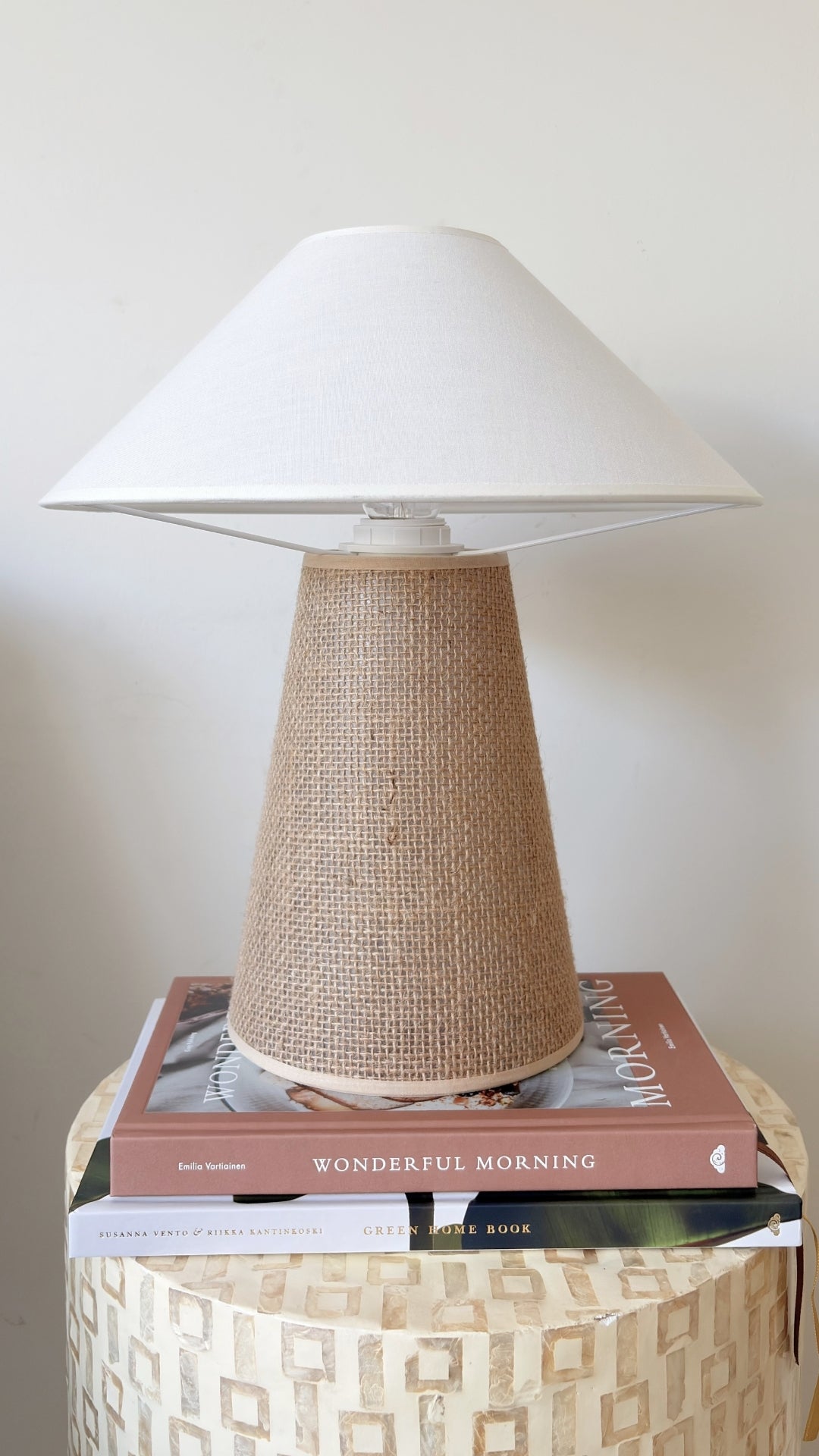 Table lamp with woven base and white shade on a patterned side table