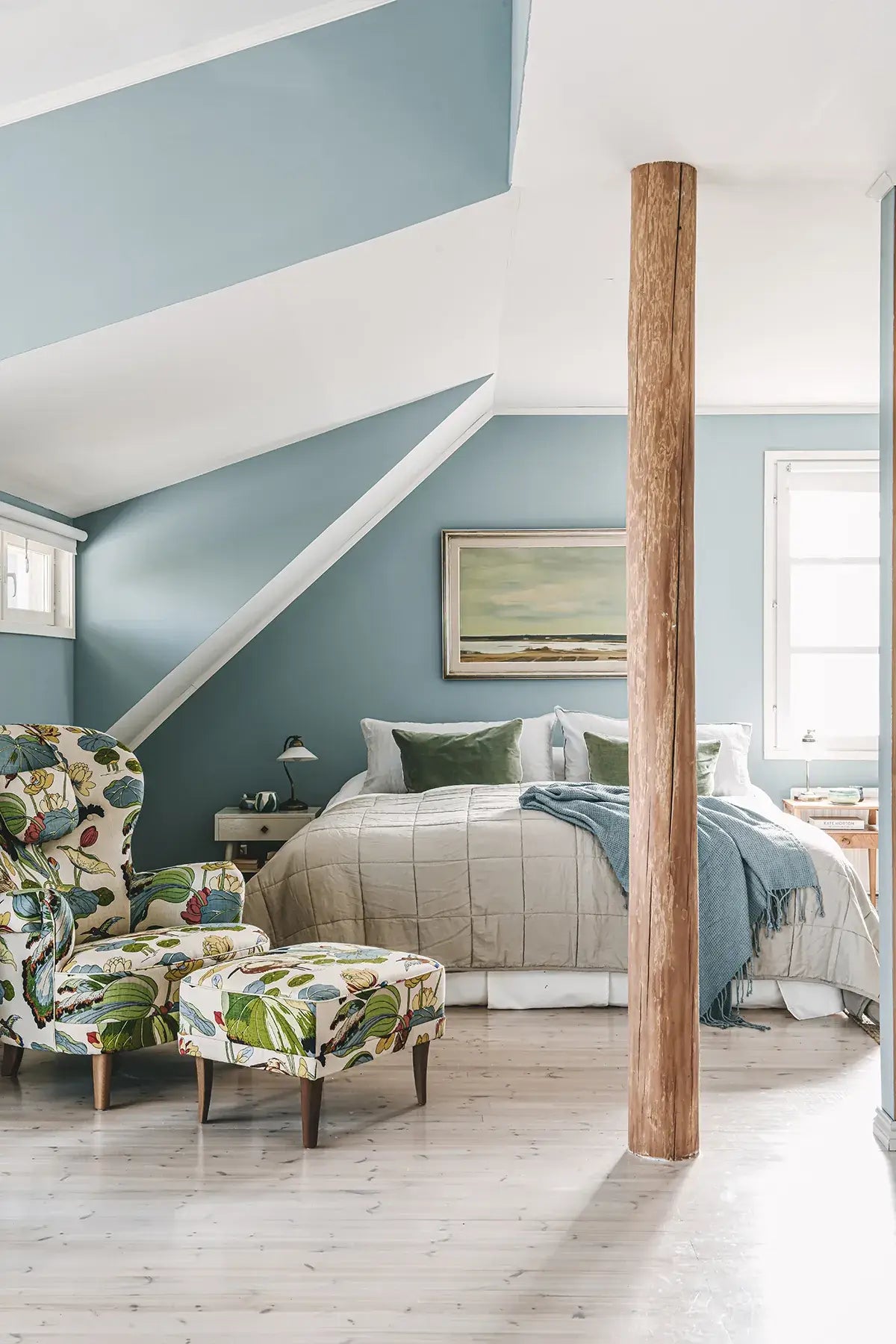 Cozy bedroom with a four-poster bed, floral armchair, and ottoman.