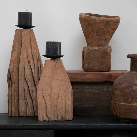 Wooden vases and candle holders on a wooden shelf against a white wall.