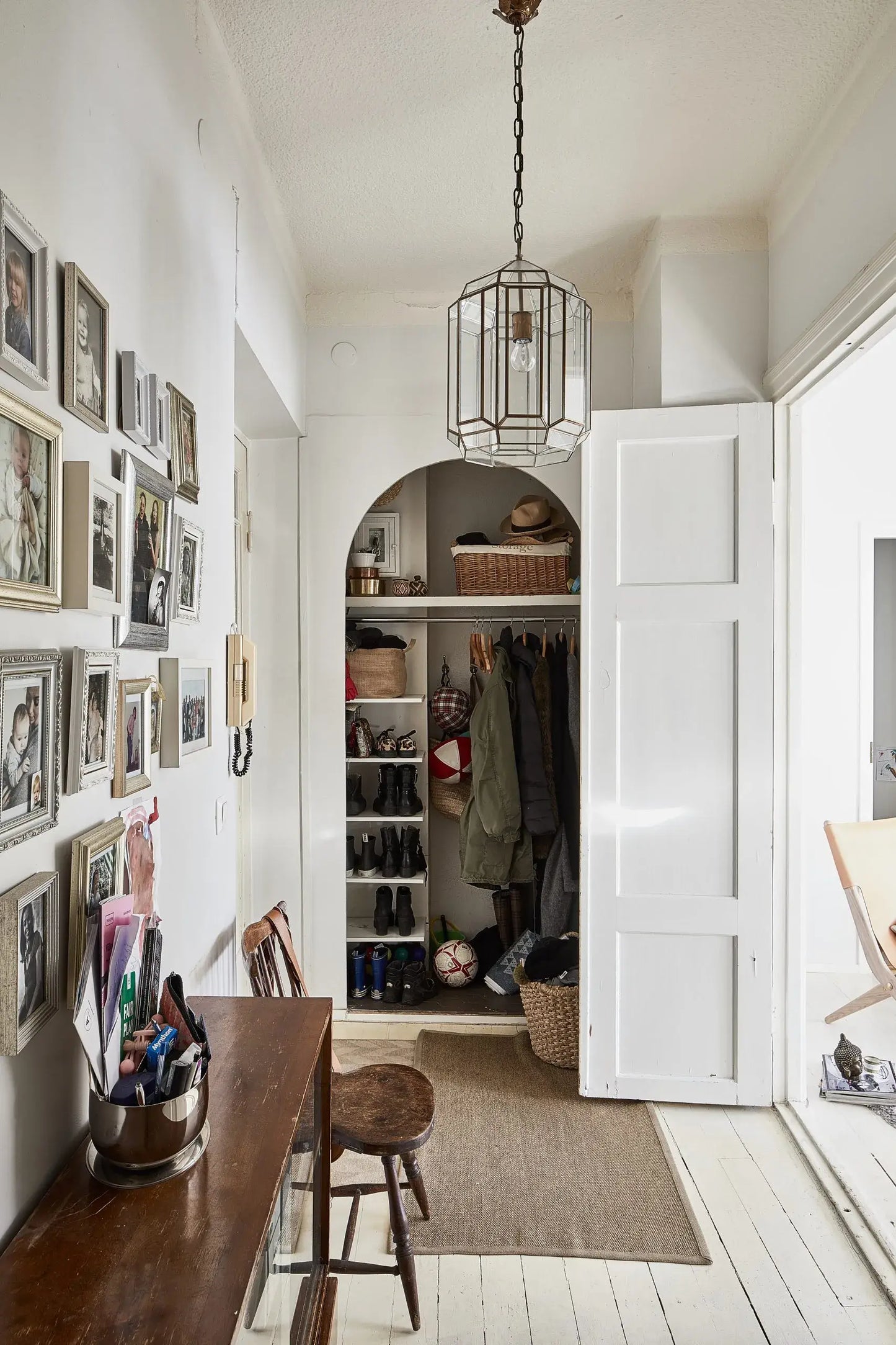 Entryway with open closet, wooden table, and framed pictures on the wall.