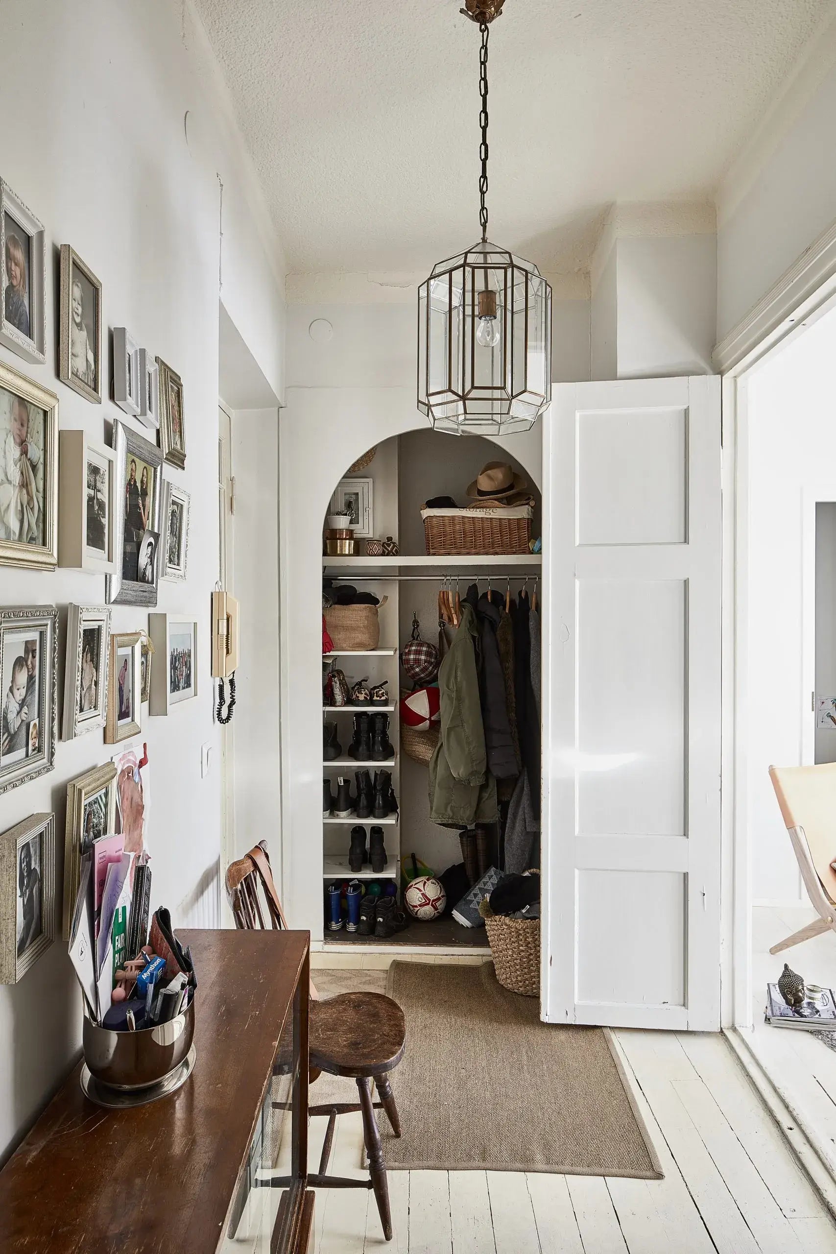 Entryway with open closet, wooden table, and framed pictures on the wall.