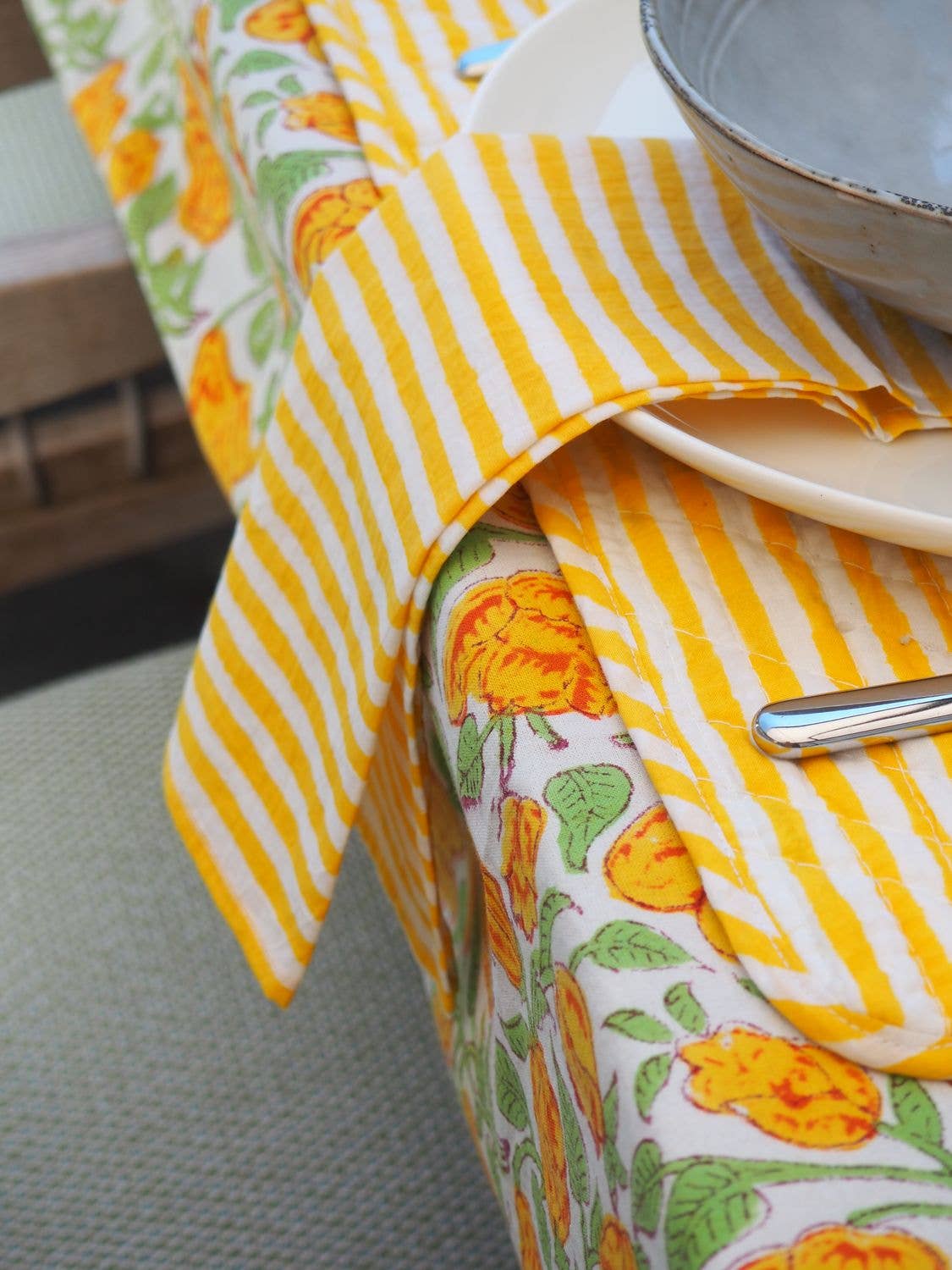 Yellow and white striped tablecloth with floral patterns on a table.