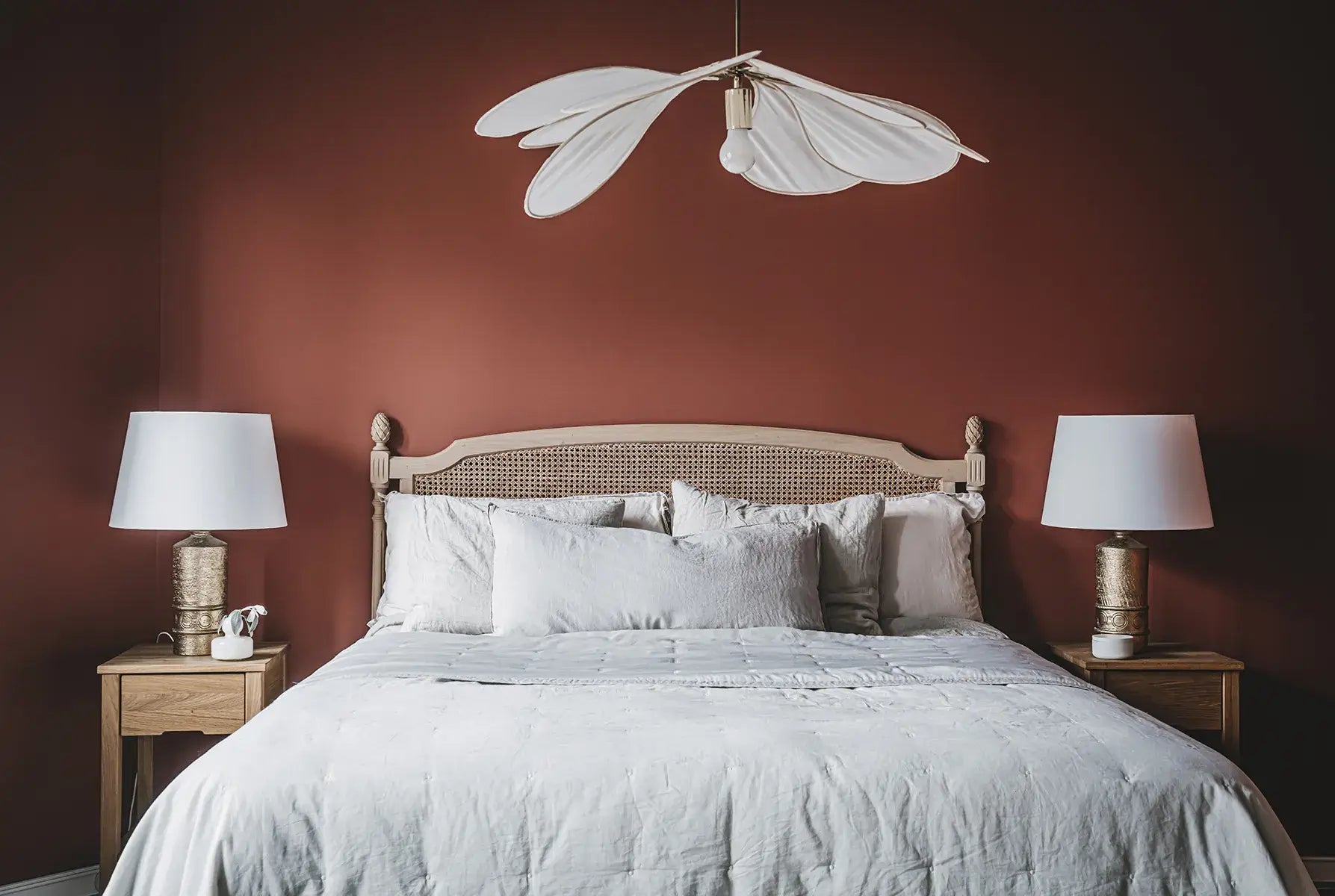 Bedroom with a bed, nightstands, and lamps against a red wall.
