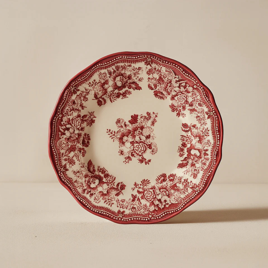 Faustine antique red floral dinner plate displayed on a cream-toned pedestal, highlighting the romantic 2026 Antique Rose trend and high-gloss finish.