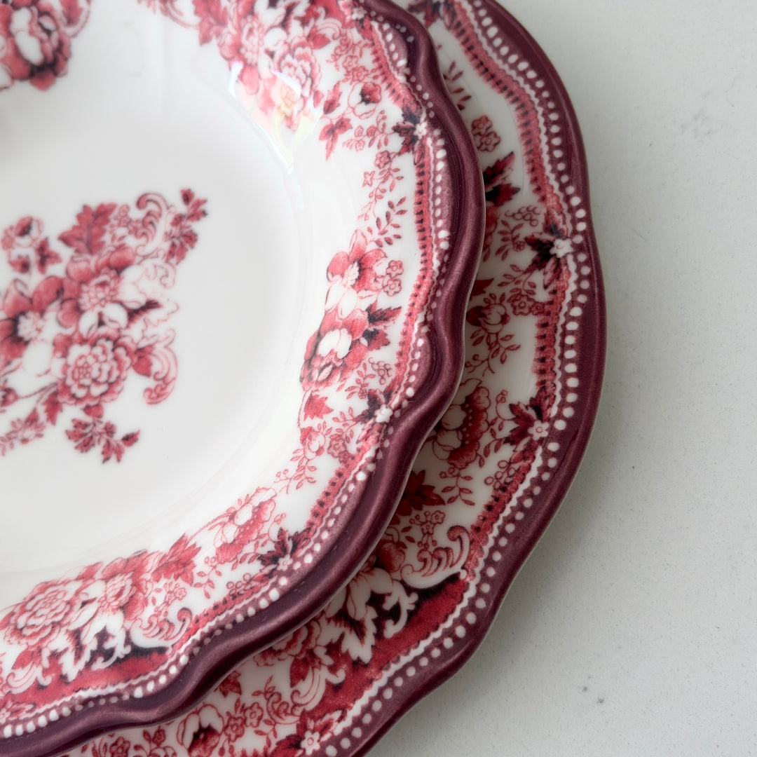 Two red and white patterned plates stacked on a light gray surface