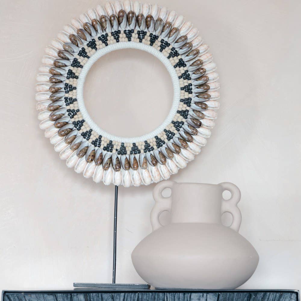 Decorative wreath with shell and bead details on a plain background