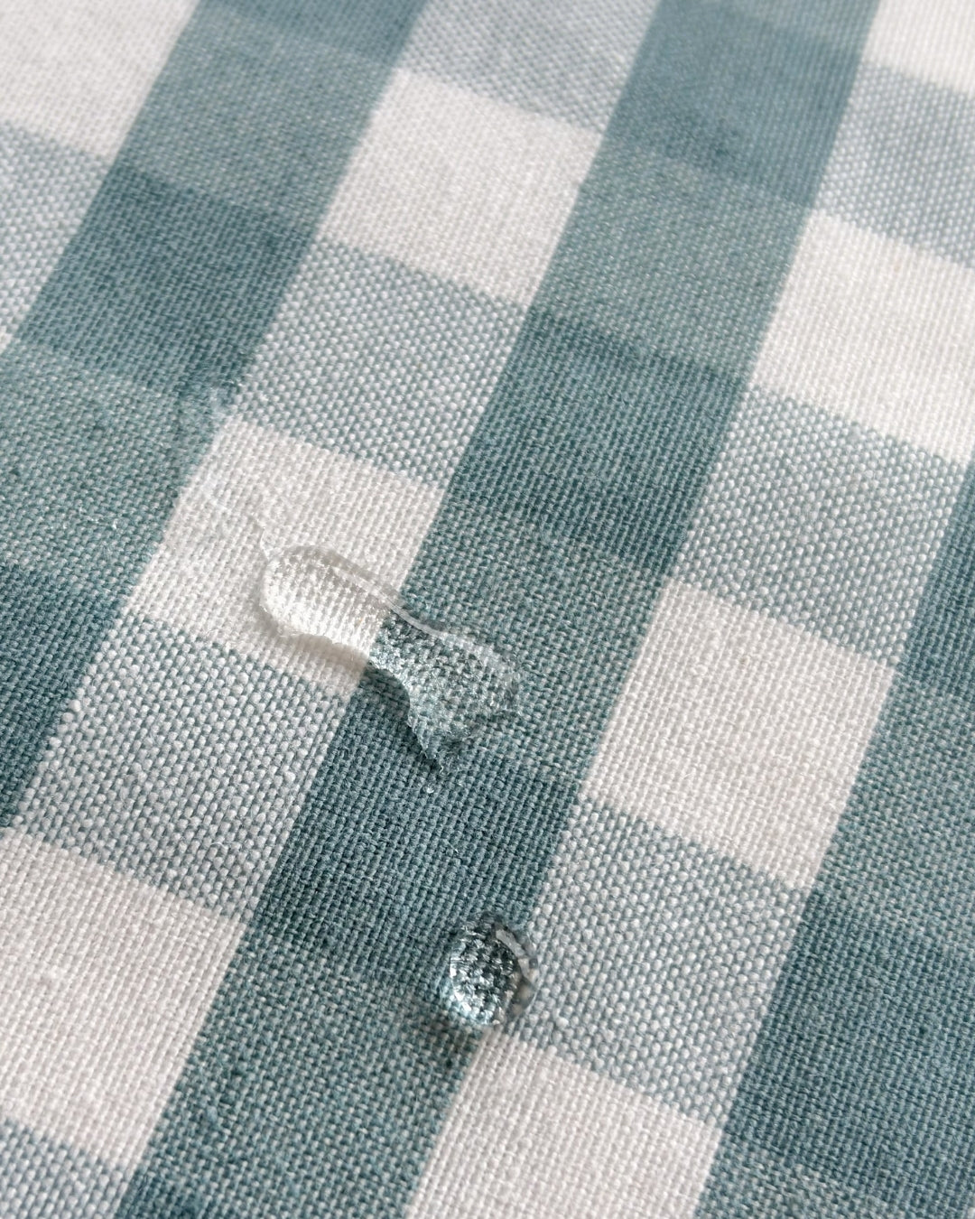 Aquamarine gingham cushions styled on an outdoor garden lounge, showcasing splash-proof resilience.