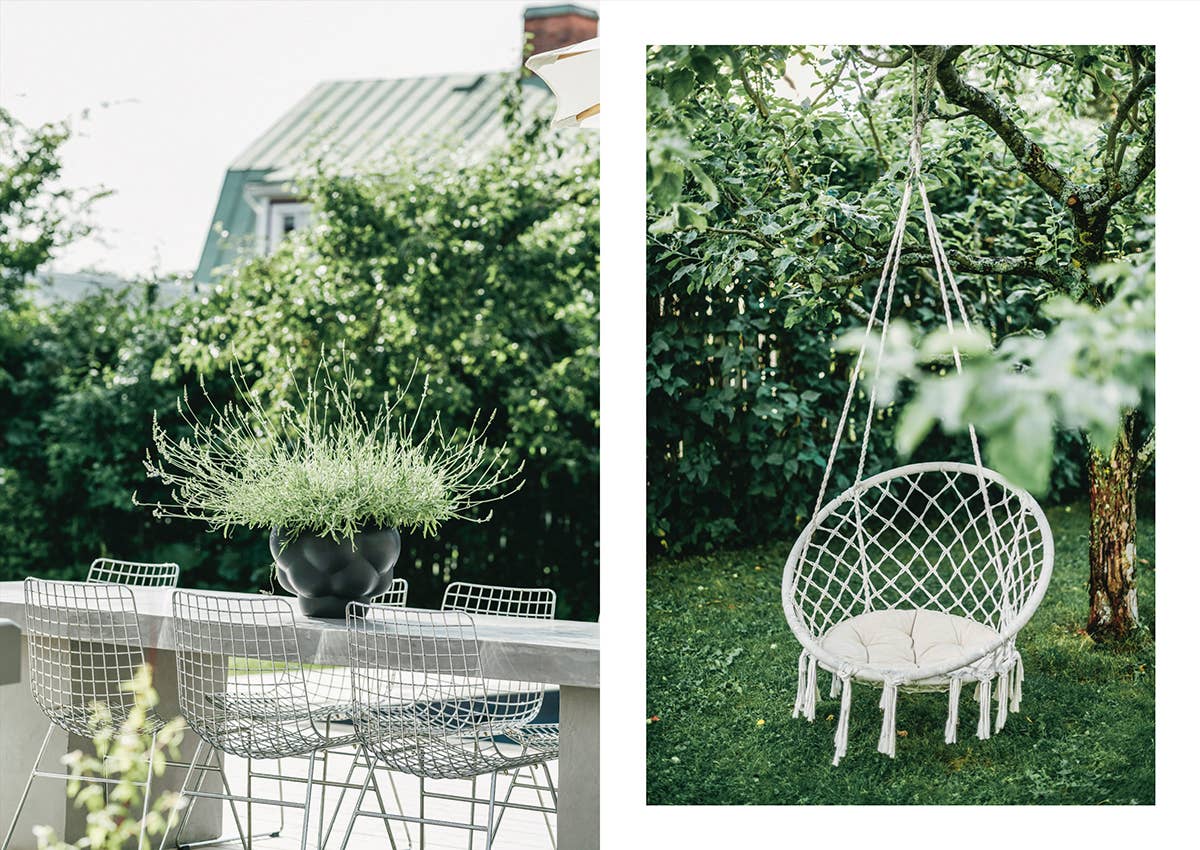 Outdoor setting with a dining table and chairs on one side and a hanging chair on the other, surrounded by greenery.