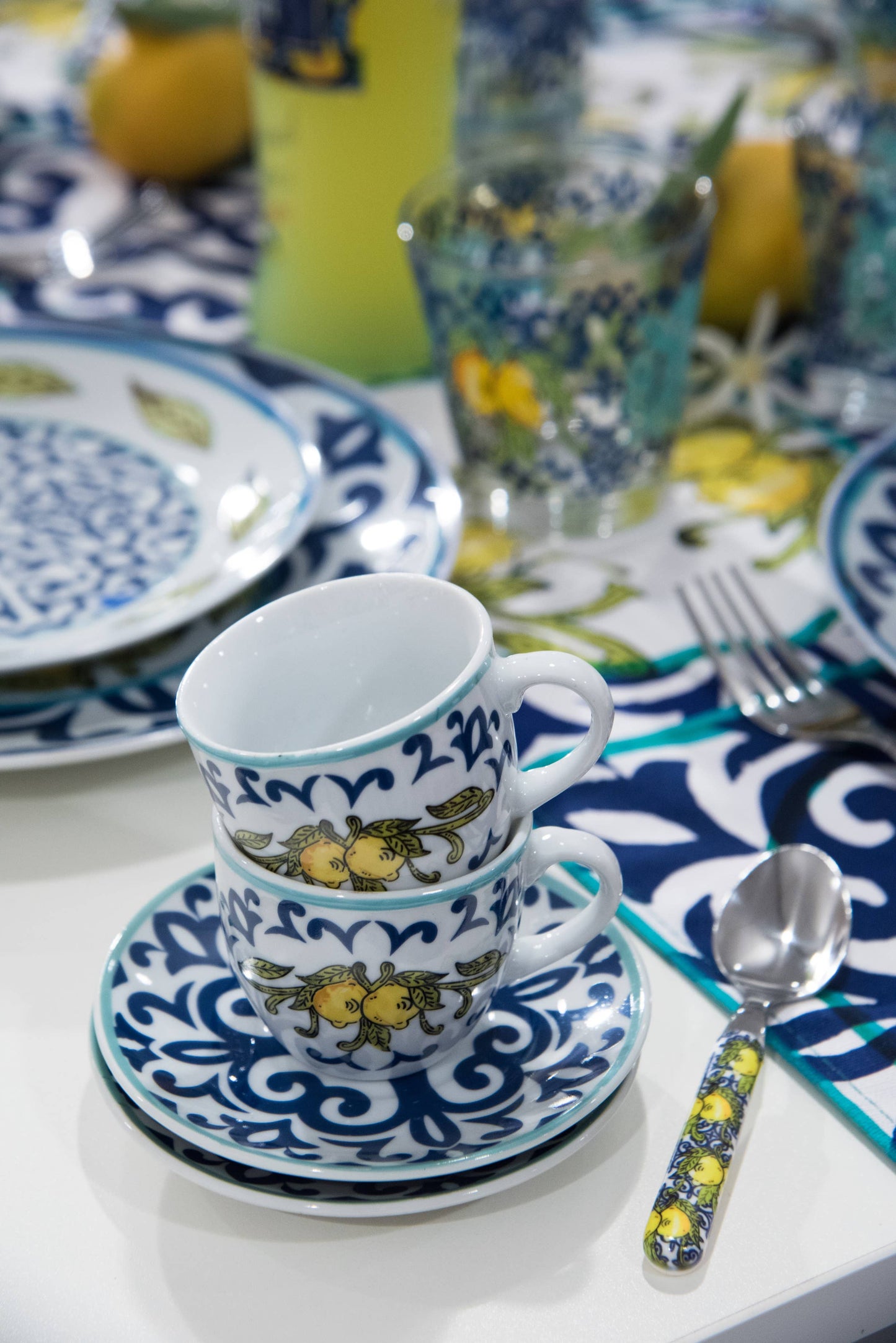 Ceramic cup and saucer with decorative elements on a table setting with lemons and blue patterns.