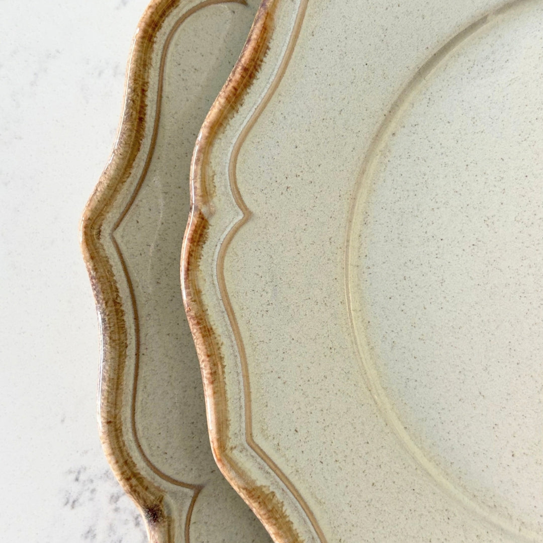 Close up of beige stoneware dessert plate with rustic glazed scalloped edge