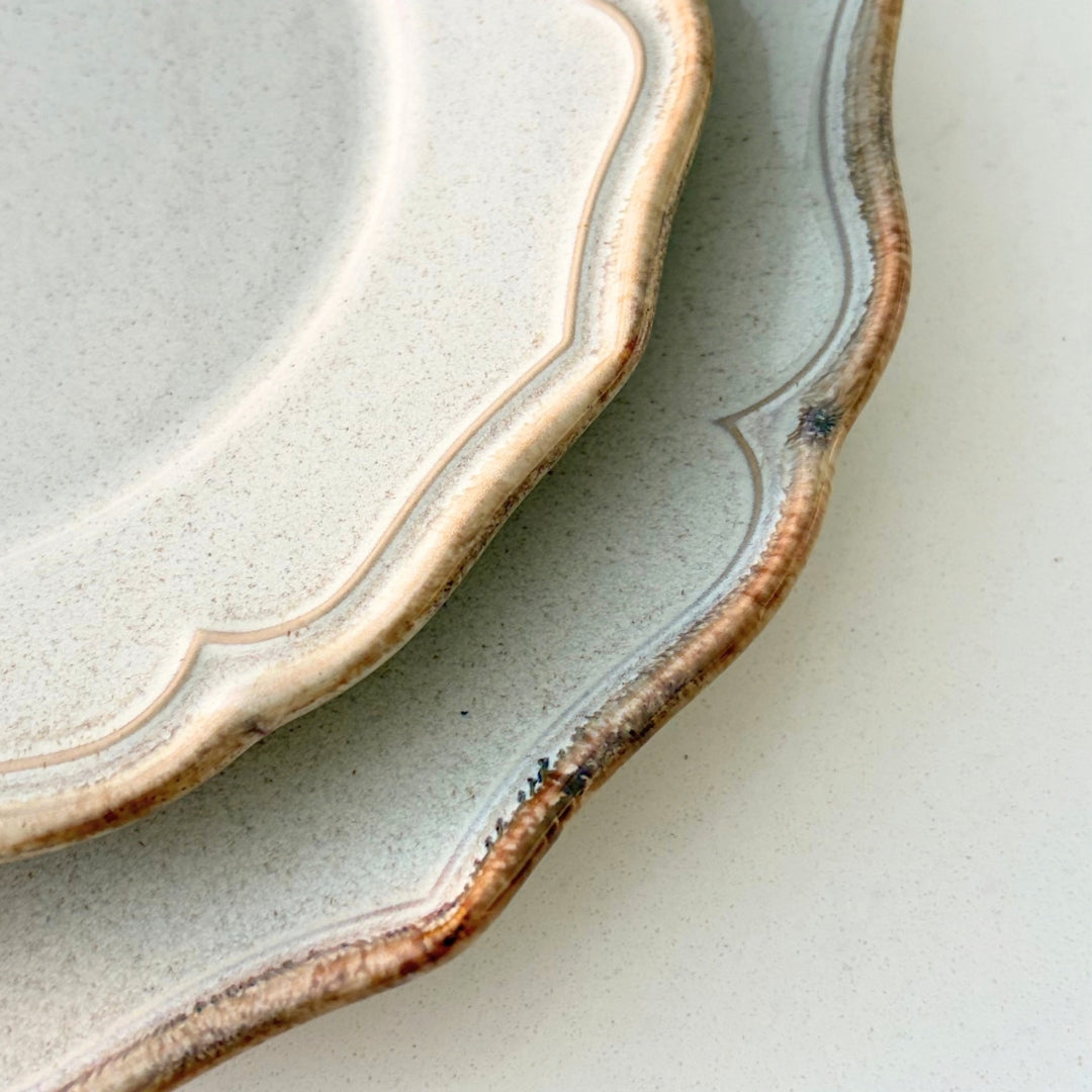 Close up of decorative scalloped edge on beige stoneware dessert plate