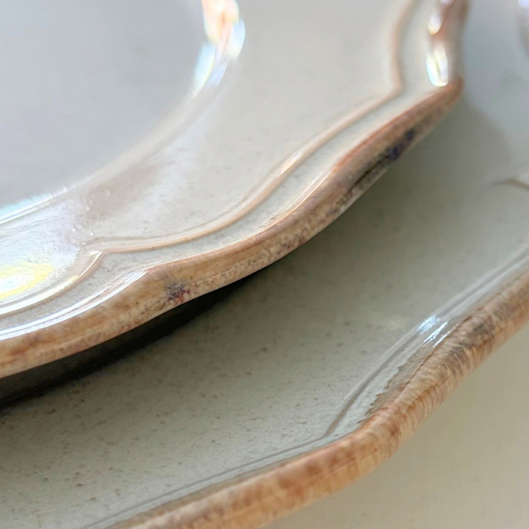 Beige stoneware dinner plate detail showing glossy glaze and textured scalloped edge
