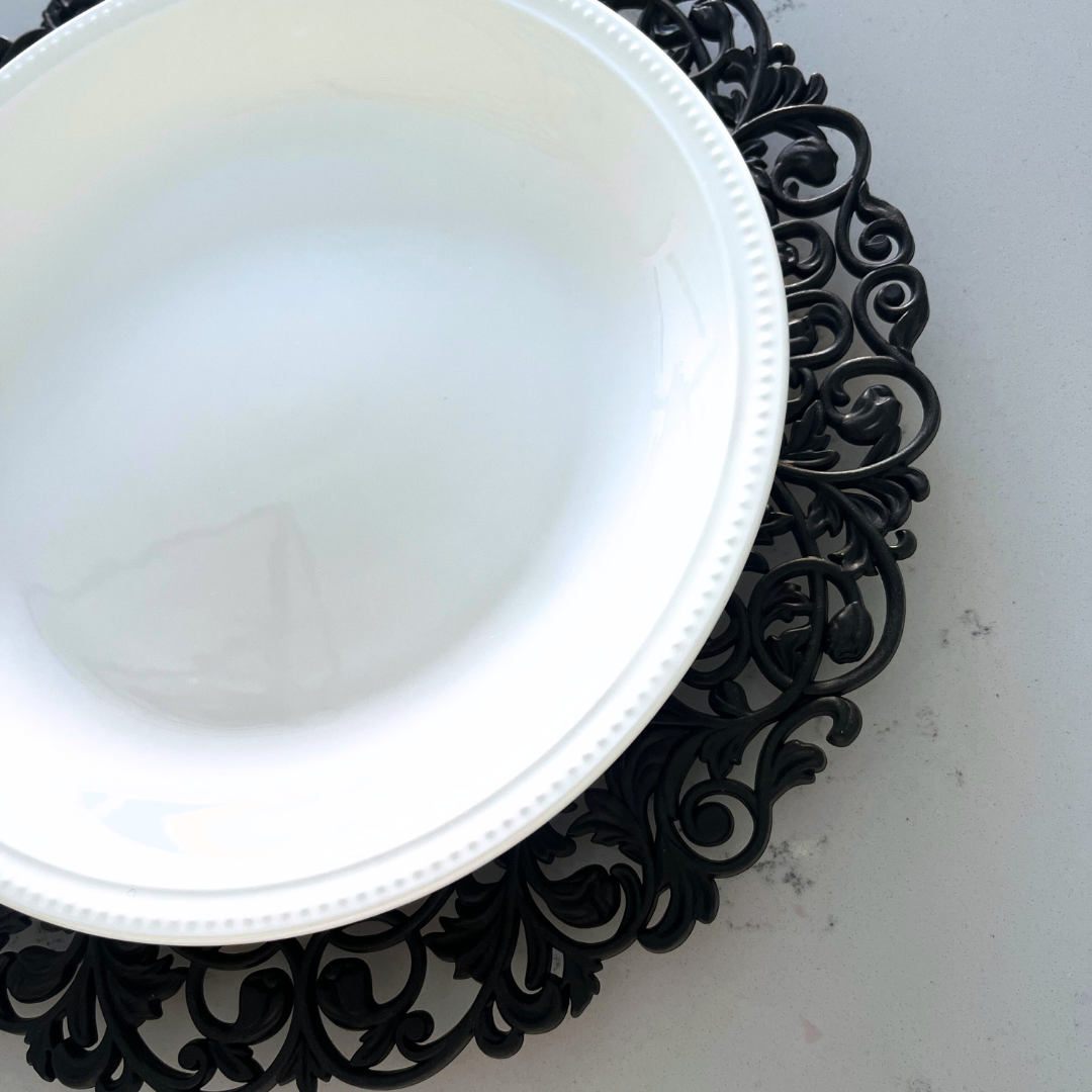 Close-up side view of black Baroque charger plate with white dinnerware
