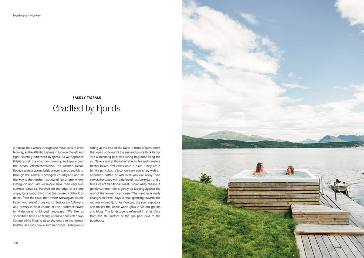 Two people in a hot tub by a lake with mountains in the background