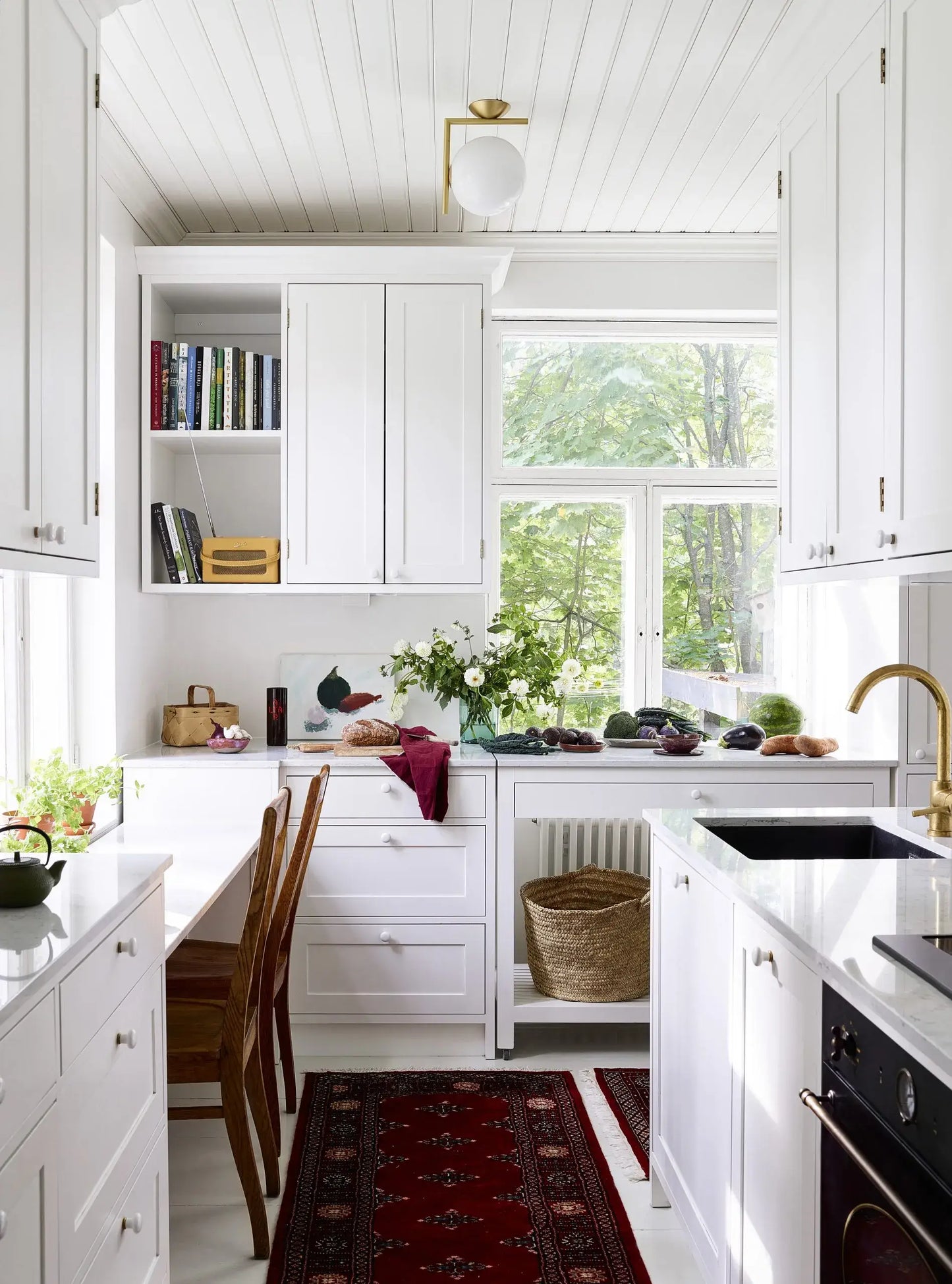 Modern kitchen with white cabinets, a window, and various items on the countertops.