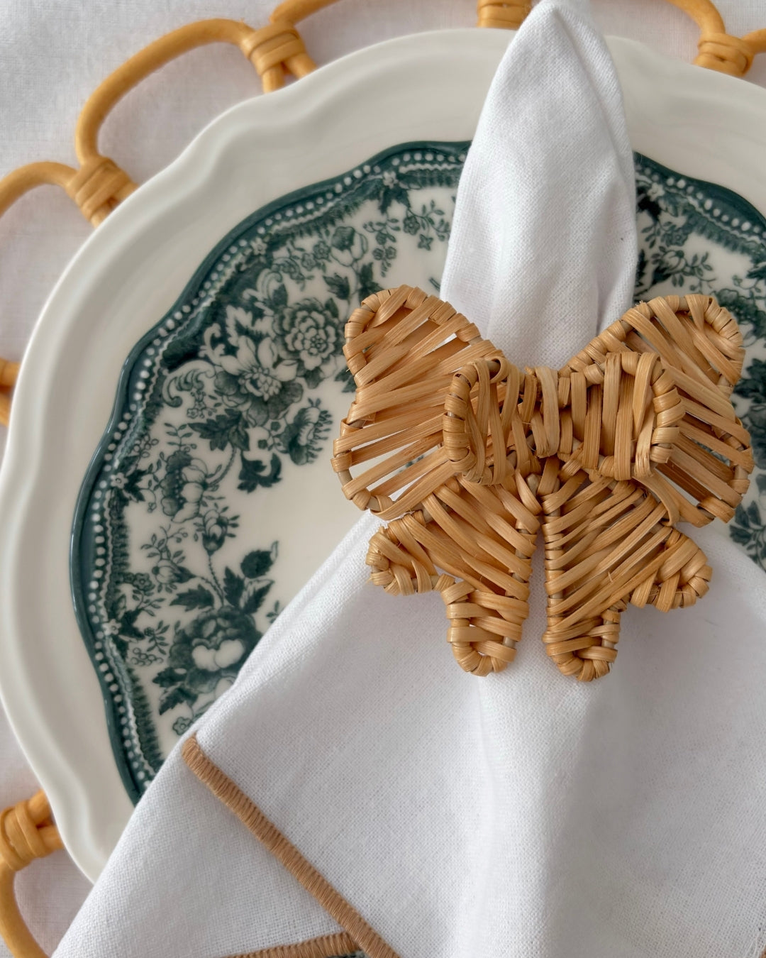 Double Bow Rattan Napkin Ring styled with a white cloth napkin for an elegant natural tablescape