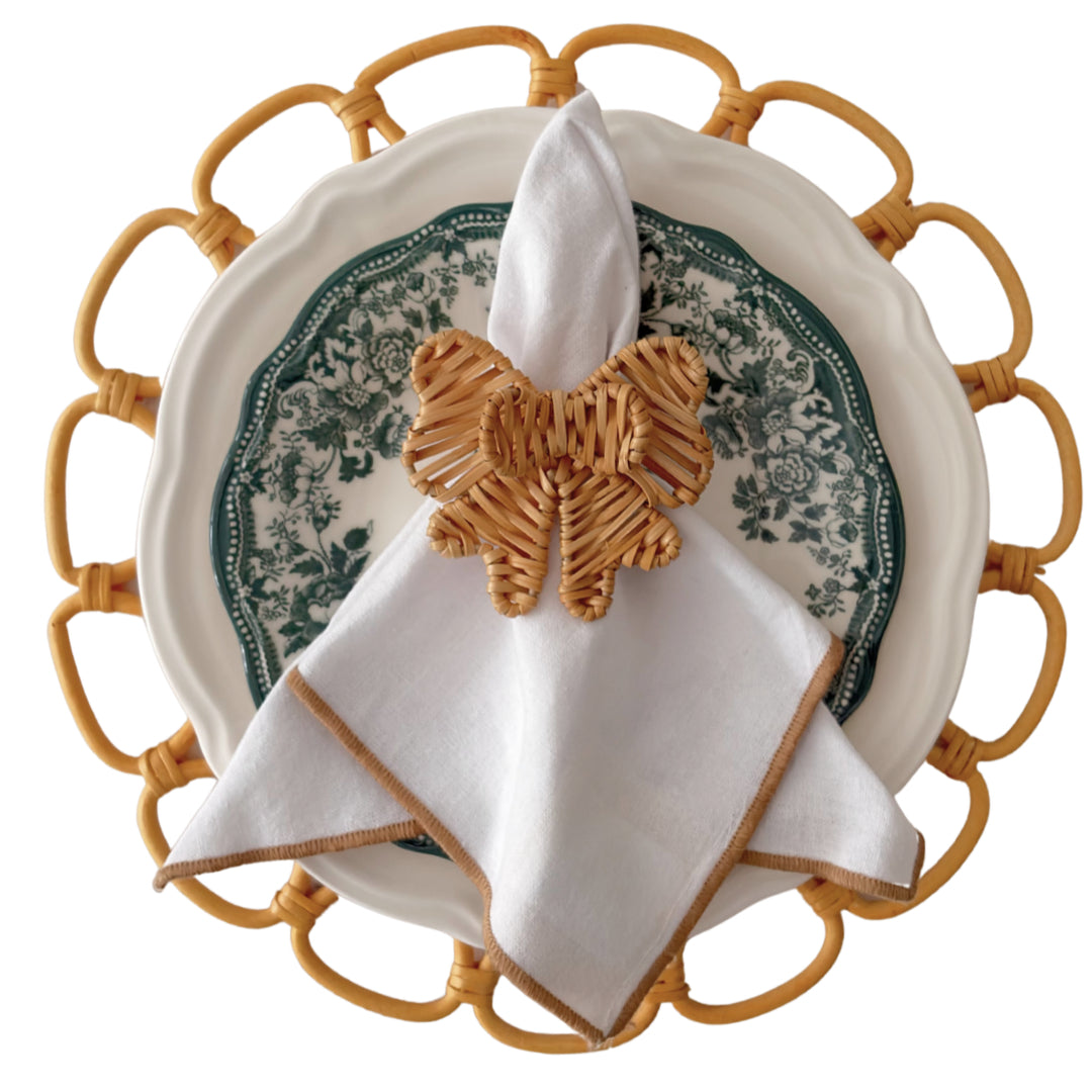 Double Bow Rattan Napkin Ring styled with a white napkin in an elegant green table setting