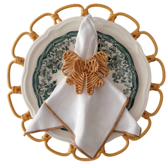 Double Bow Rattan Napkin Ring styled with a white napkin in an elegant green table setting