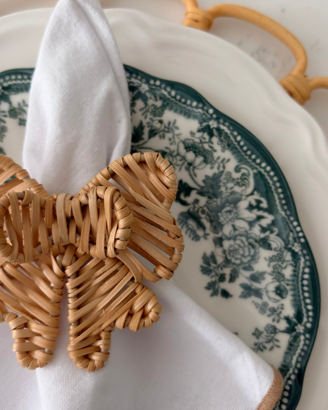 Close-up of a handwoven Double Bow Rattan Napkin Ring styled as natural table decor