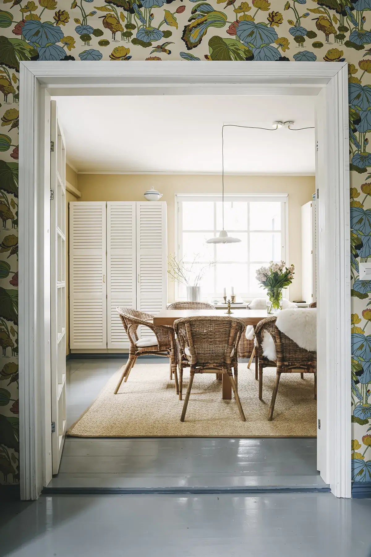 Dining room with floral wallpaper and a view through an open door.