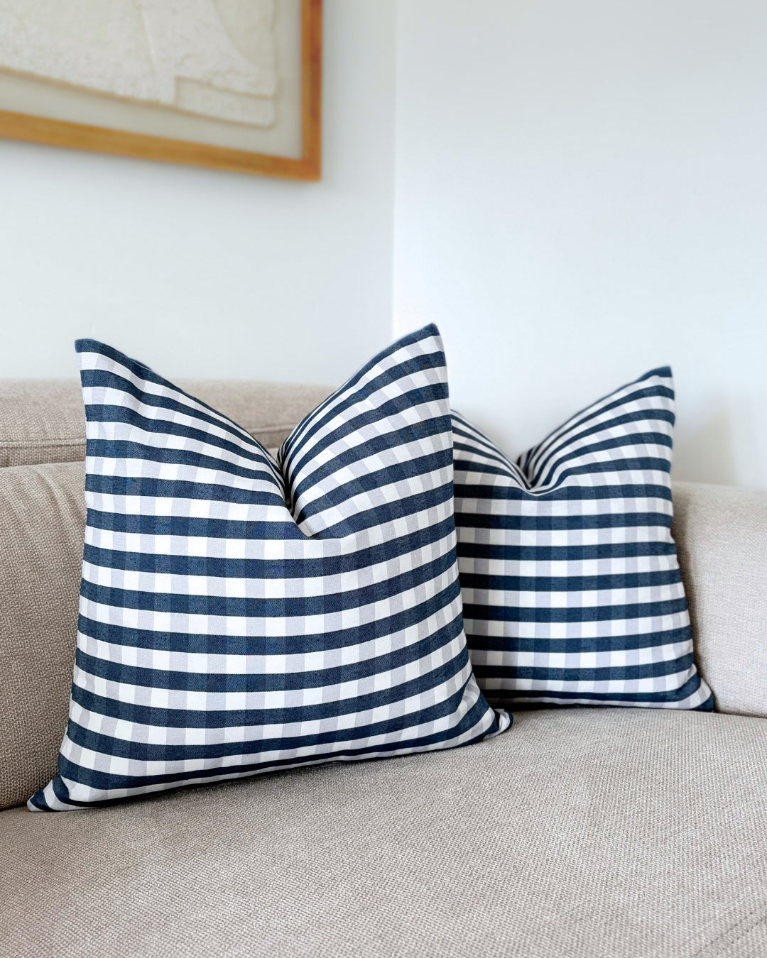 Set of 2 navy blue gingham cushion covers on beige sofa for Christmas and festive holiday living room decor.