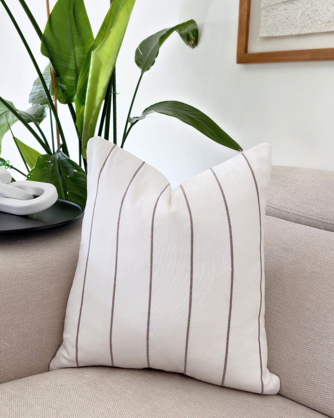 Elegant flax white cushion cover with brown accents on a neutral beige sofa.