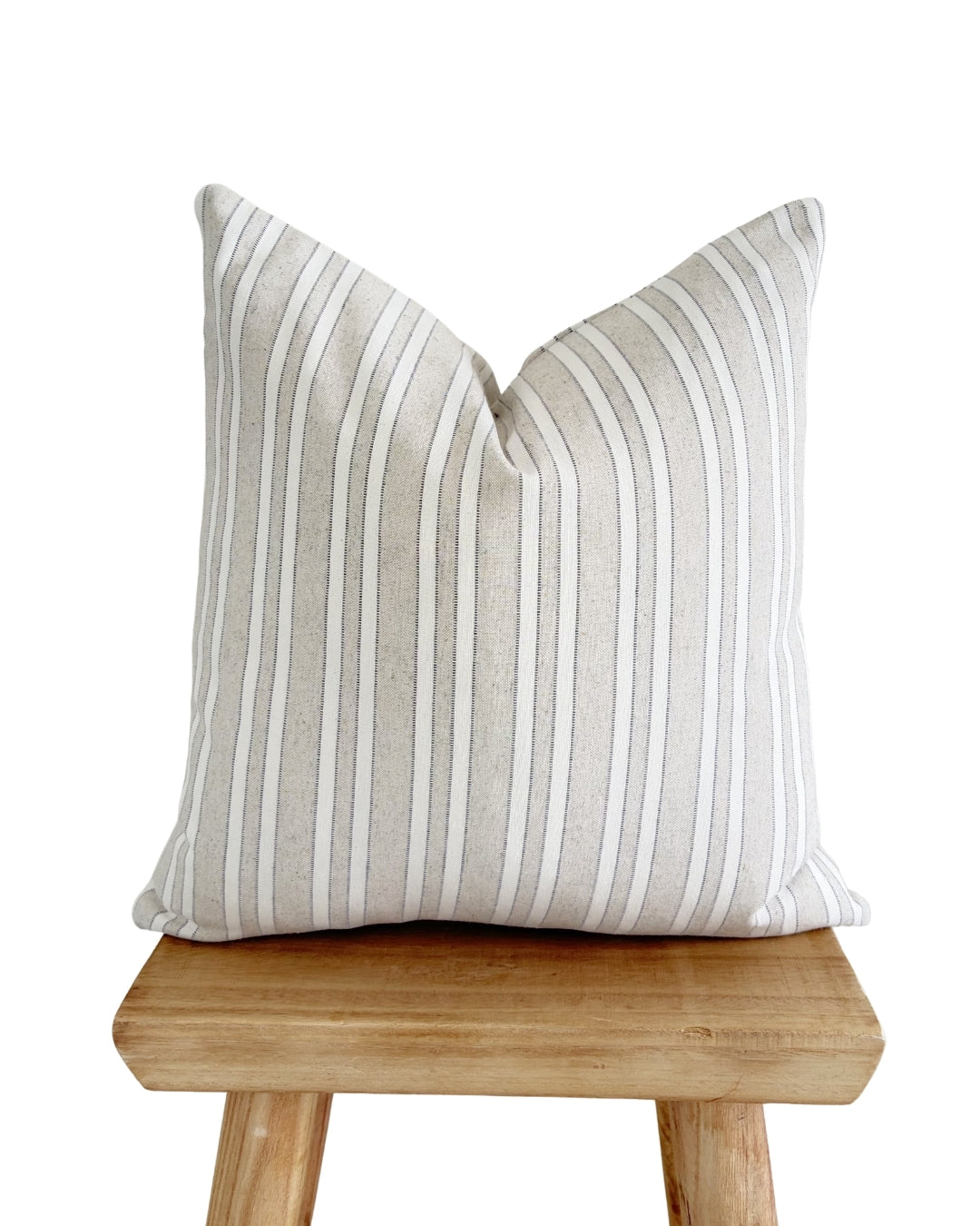 Earthy taupe woven jacquard cushion cover styled on a rustic wood stool for a Mediterranean home aesthetic.
