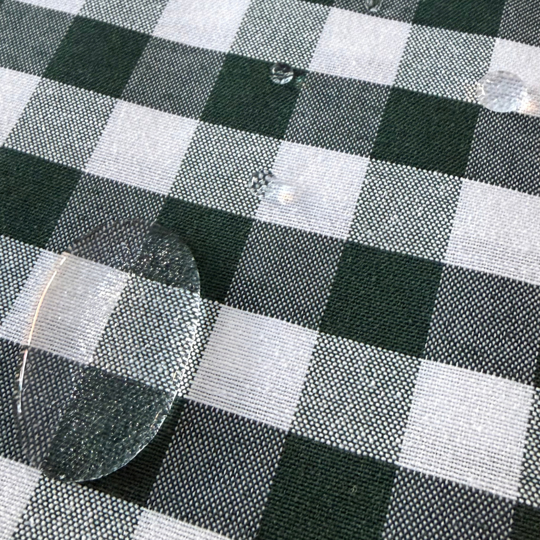 Water droplets beading on green gingham water repellent fabric.
