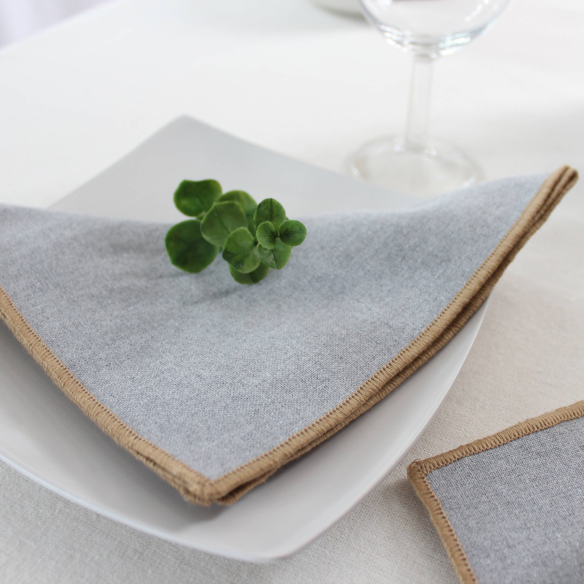 Organic modern table decor featuring silver ash grey napkins and jute trim on a contemporary dining setting.
