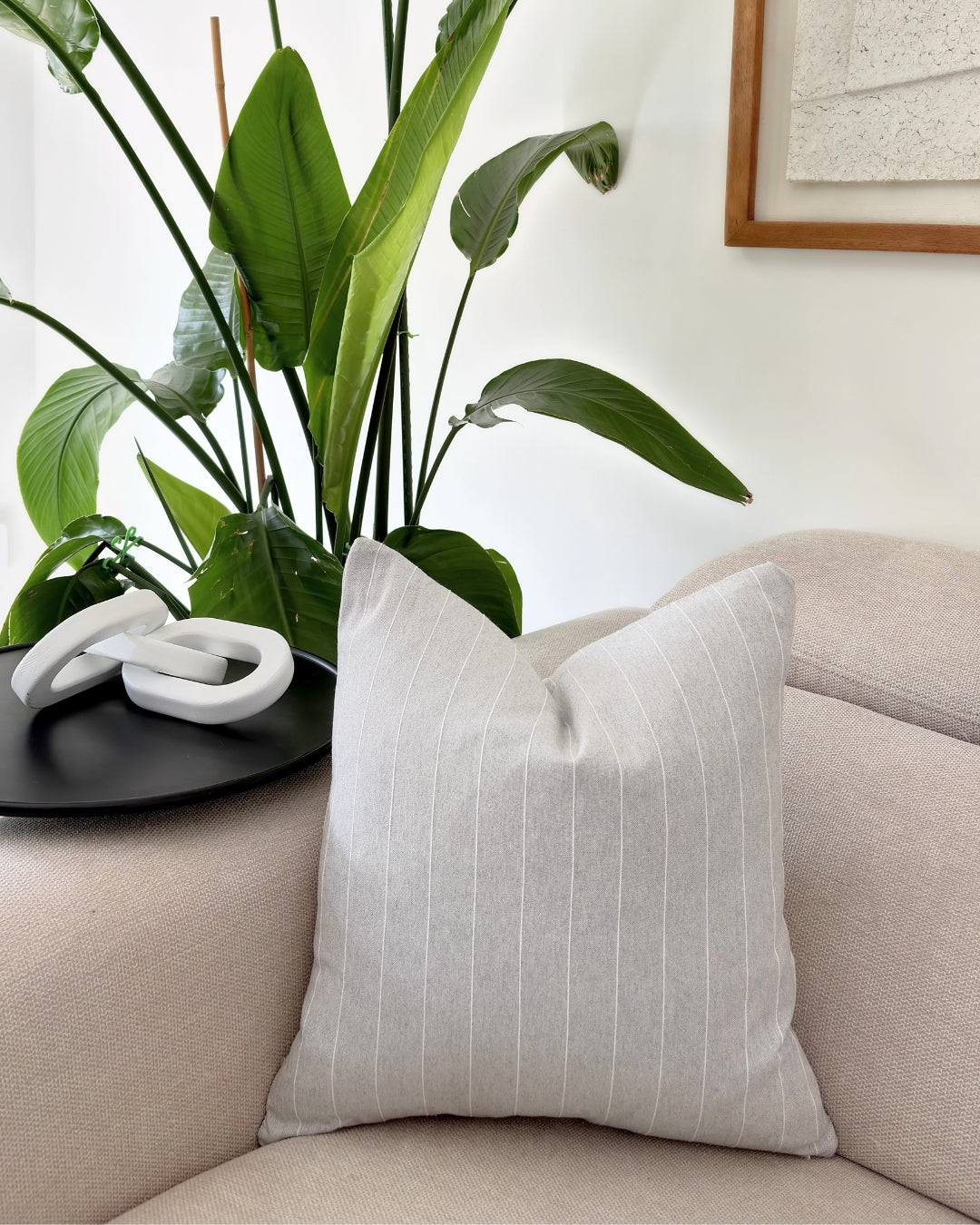 Sophisticated grey pinstripe cushion cover on a neutral beige sofa in a modern living room.