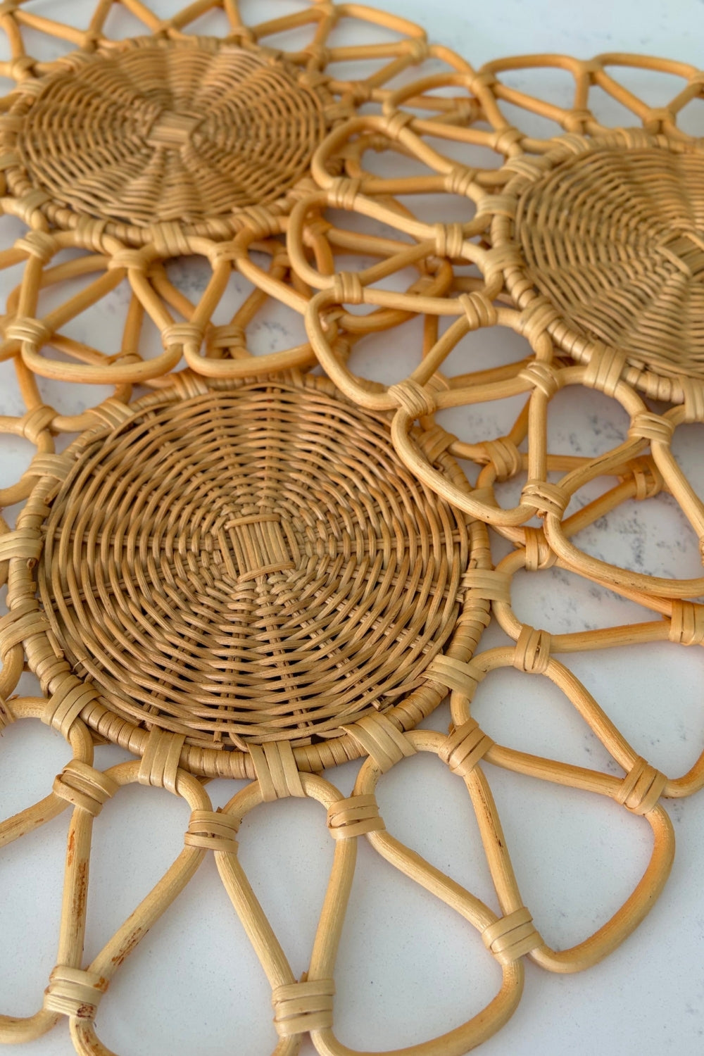 Detailed close-up of three circular woven centers and radial lattice openwork pattern on a natural rattan underplate.