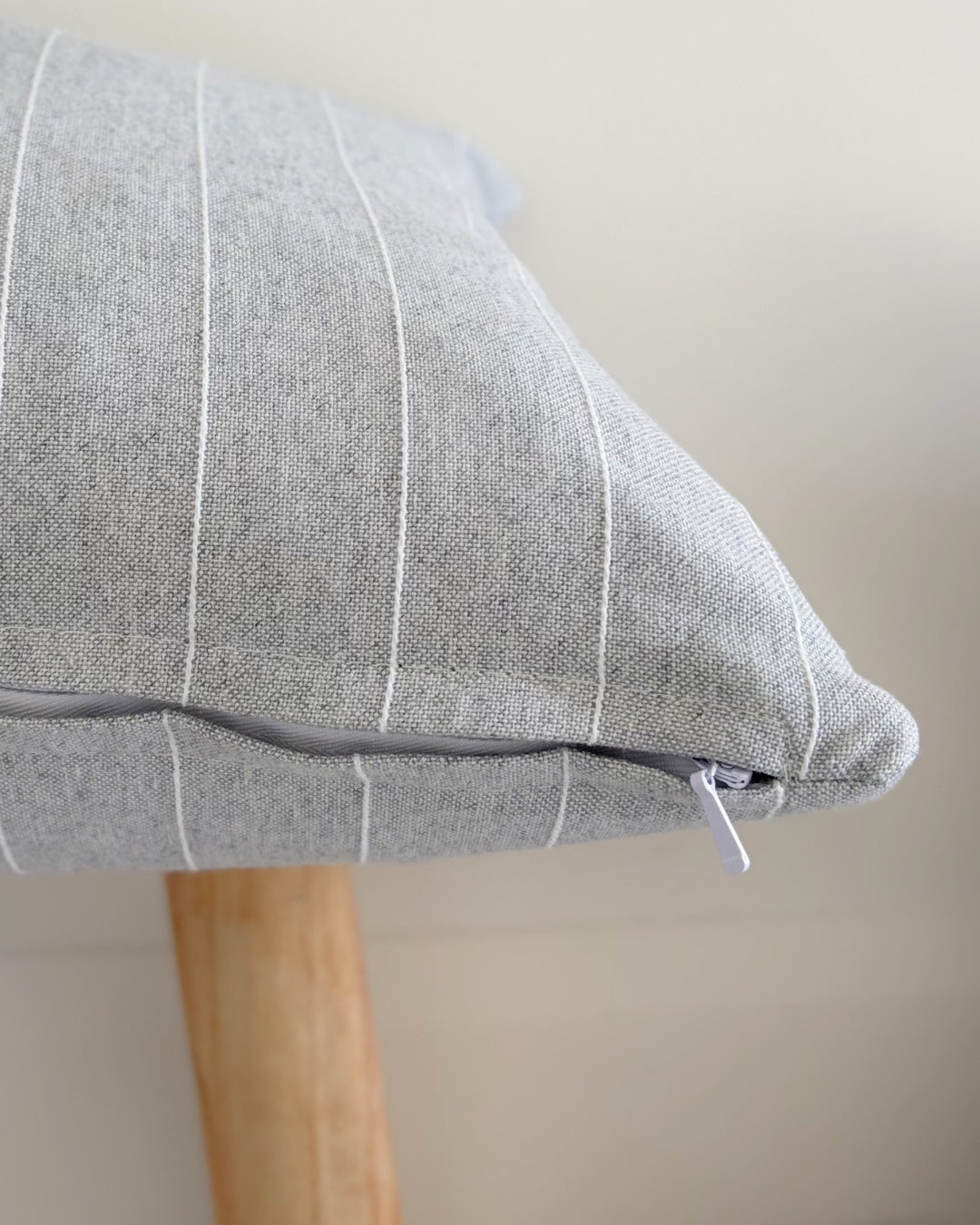 Seamless hidden zipper detail on a grey and white pinstripe cushion cover.