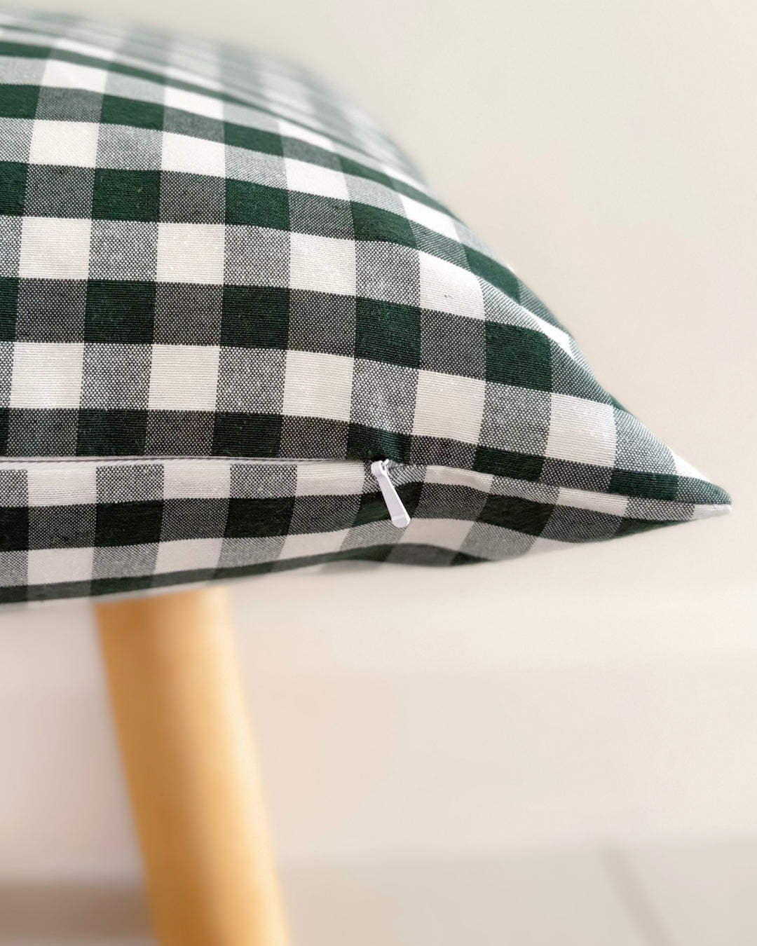 Close-up of tailored concealed hidden zipper on forest green gingham cushion cover.
