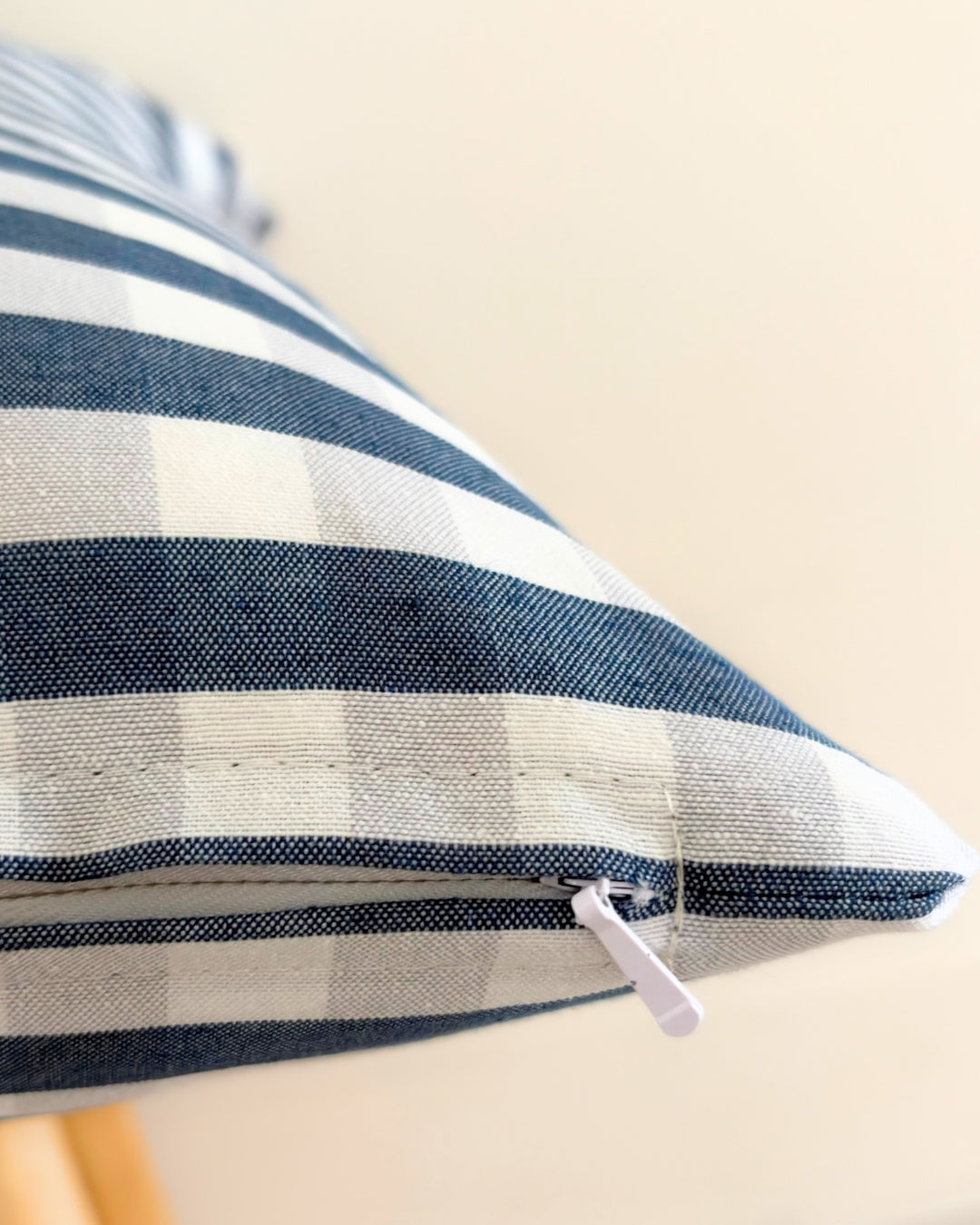 Close-up of tailored concealed hidden zipper on navy blue gingham cushion cover.