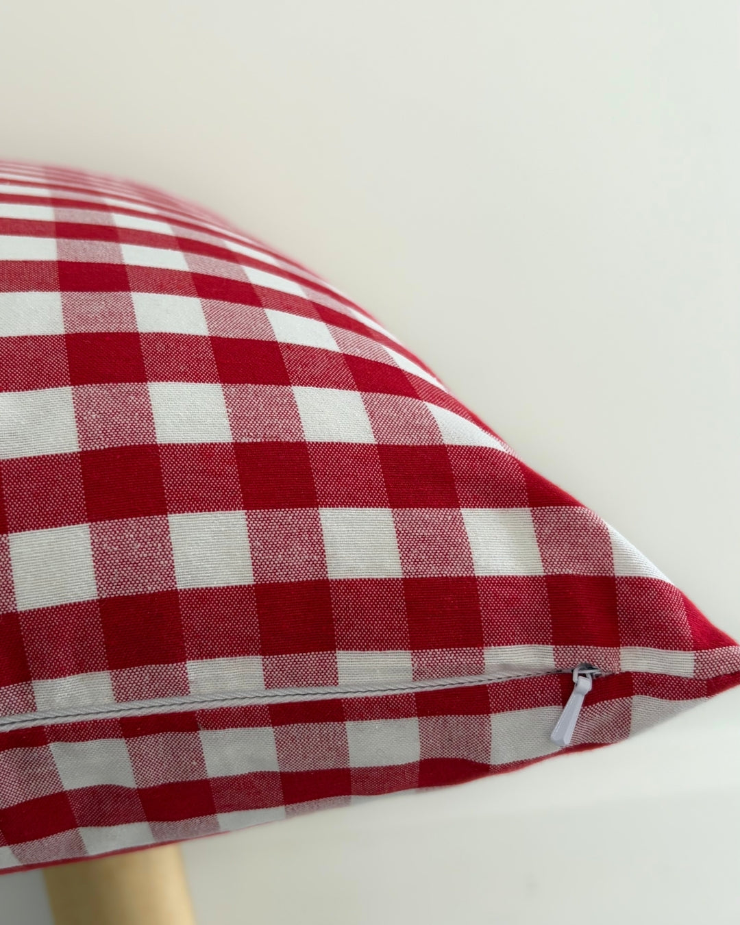 Close-up of tailored concealed hidden zipper on red gingham cushion cover.