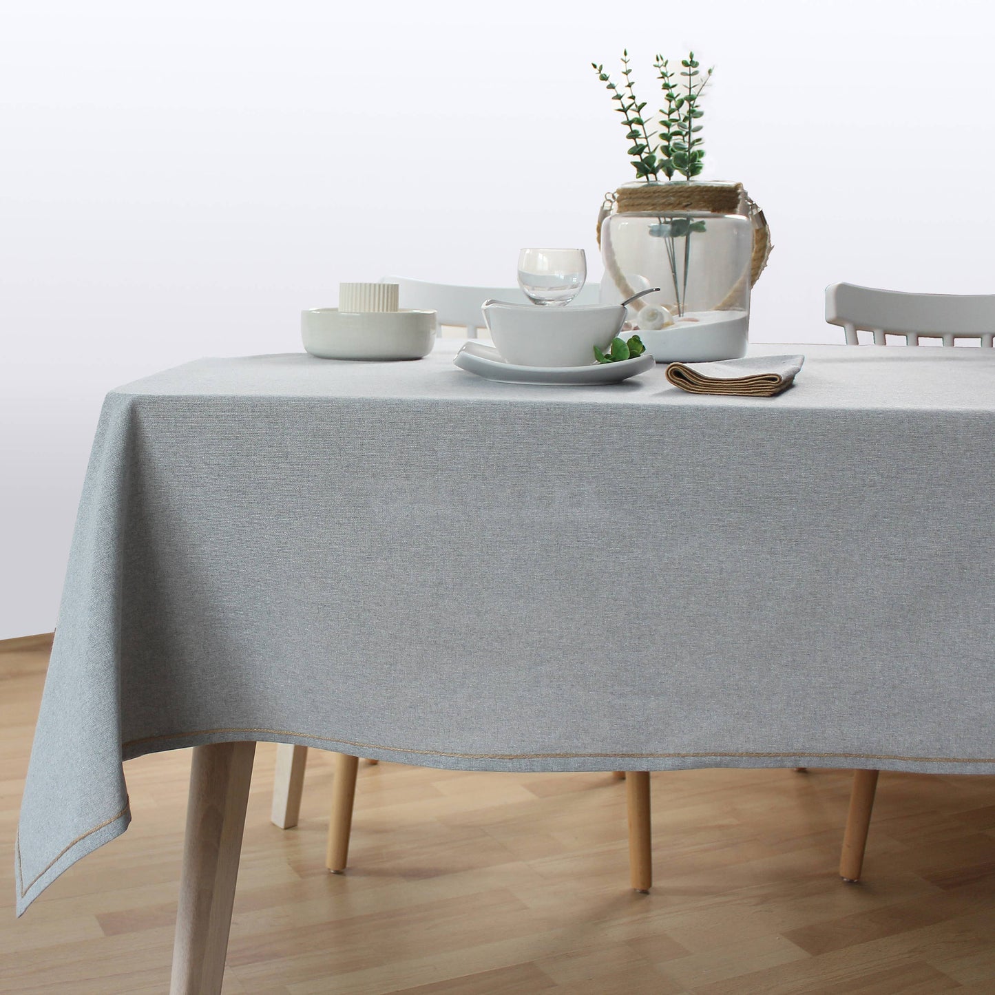 Scandinavian style dining setting with  light grey tablecloth and neutral decor